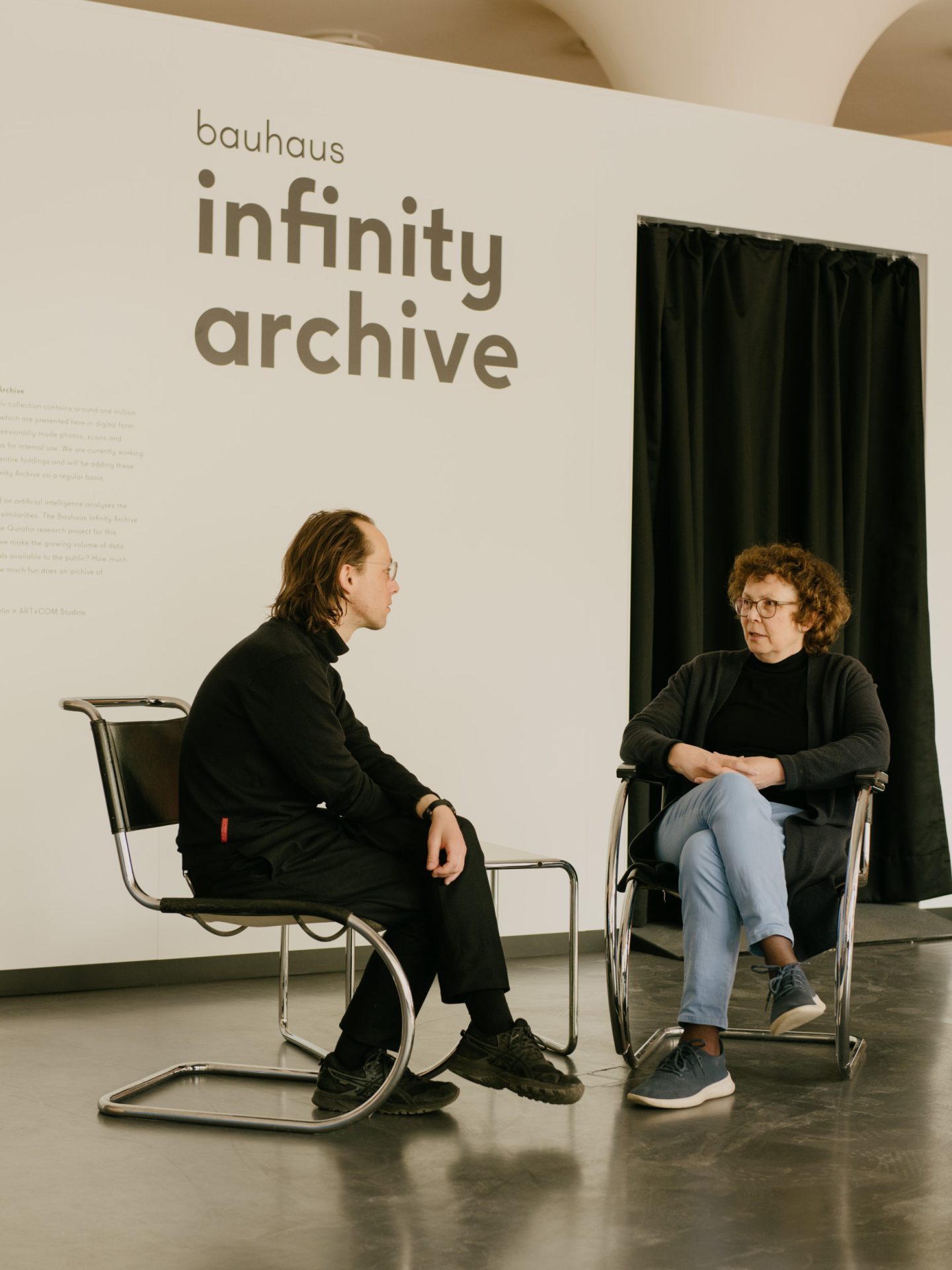 Annemarie Jaeggi und Philipp Hindahl sitzen auf Stühlen im temporary bauhaus-archiv gegenüber.