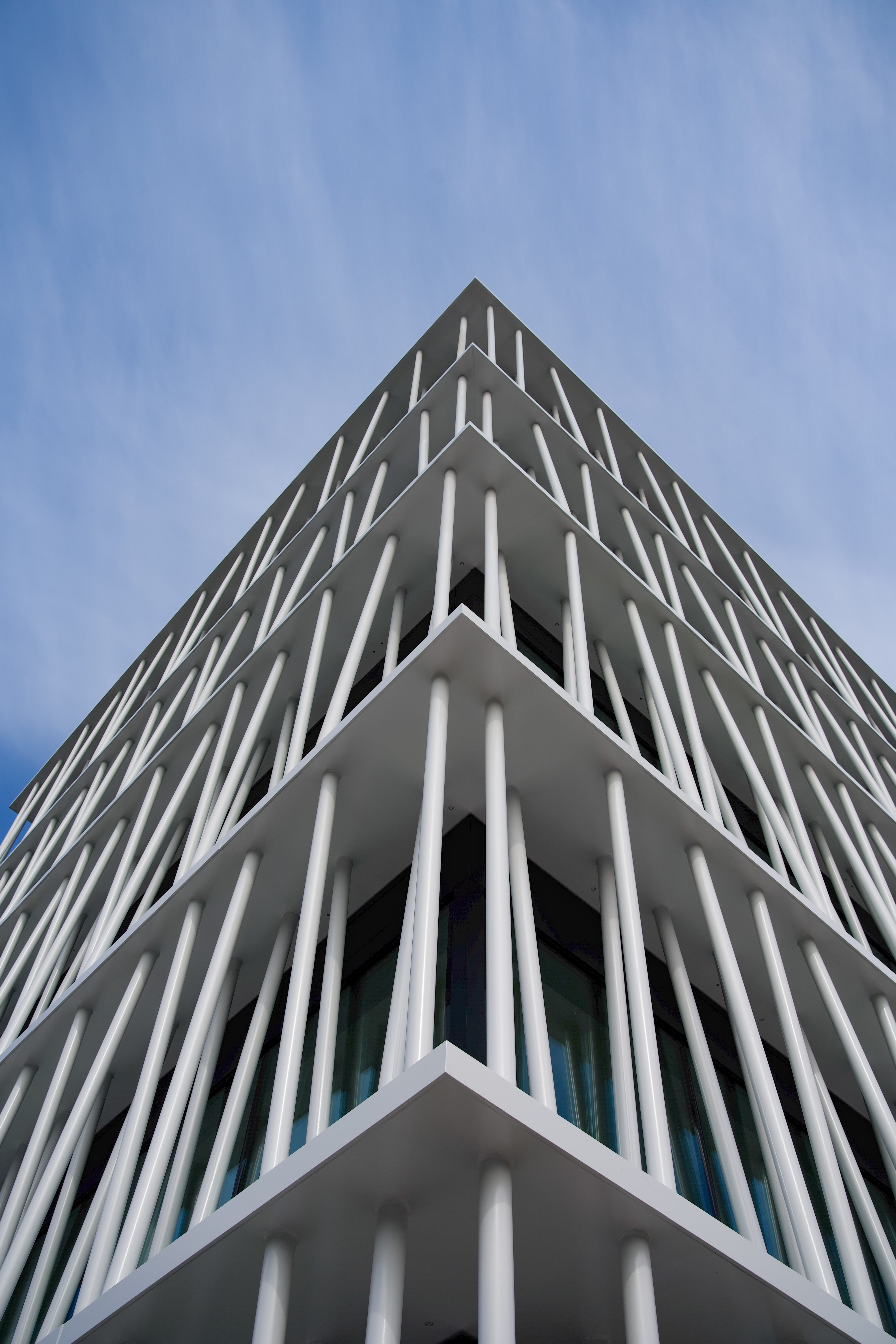 Moderne Architektur eines Gebäudes mit vertikalen weißen Streifen unter klarem Himmel.