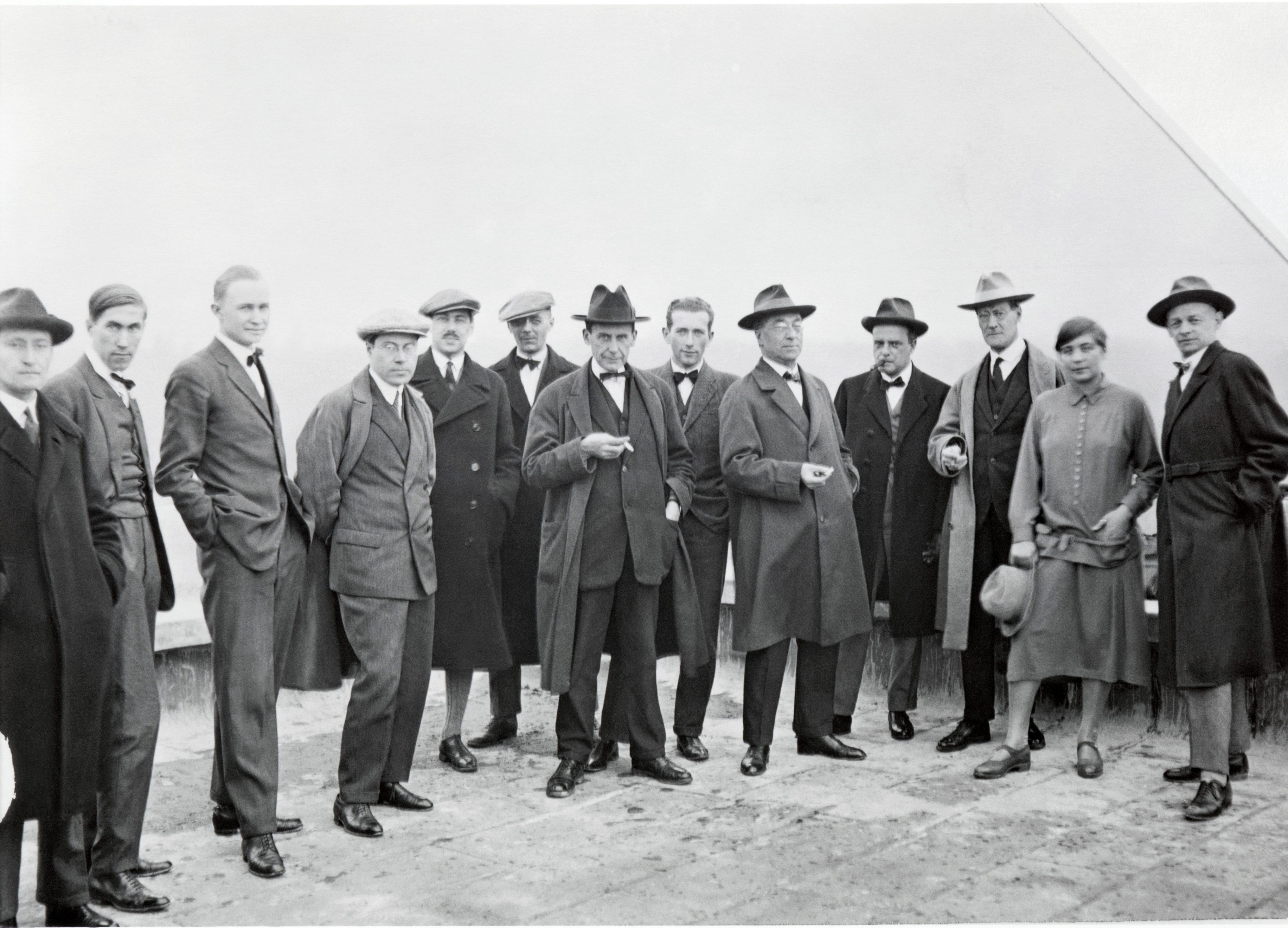 Die Bauhaus-Meister in formeller Kleidung, posierend vor neutralem Hintergrund.