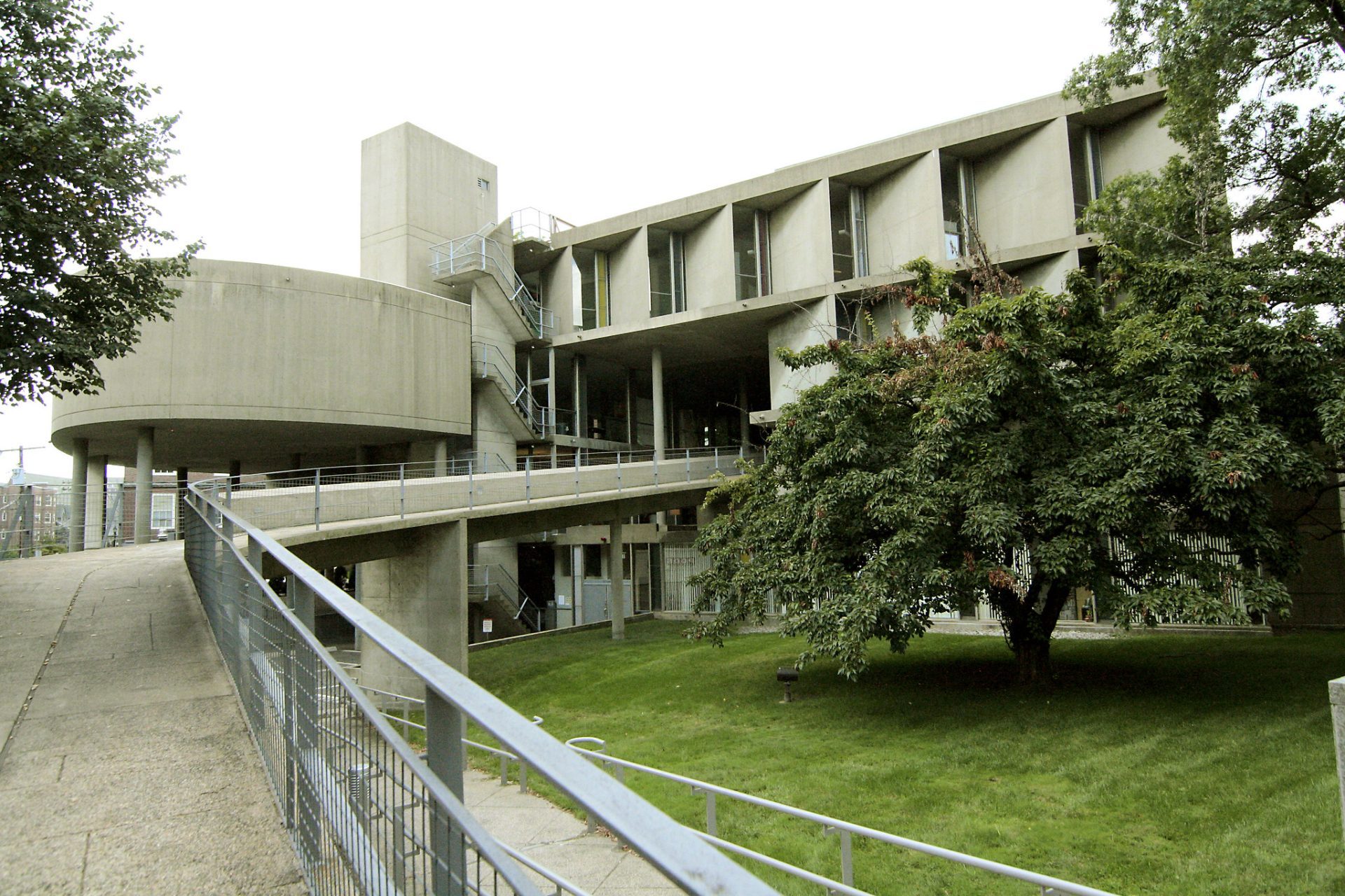 Modern architecture of a concrete building with a curved façade and a landscaped area in front.