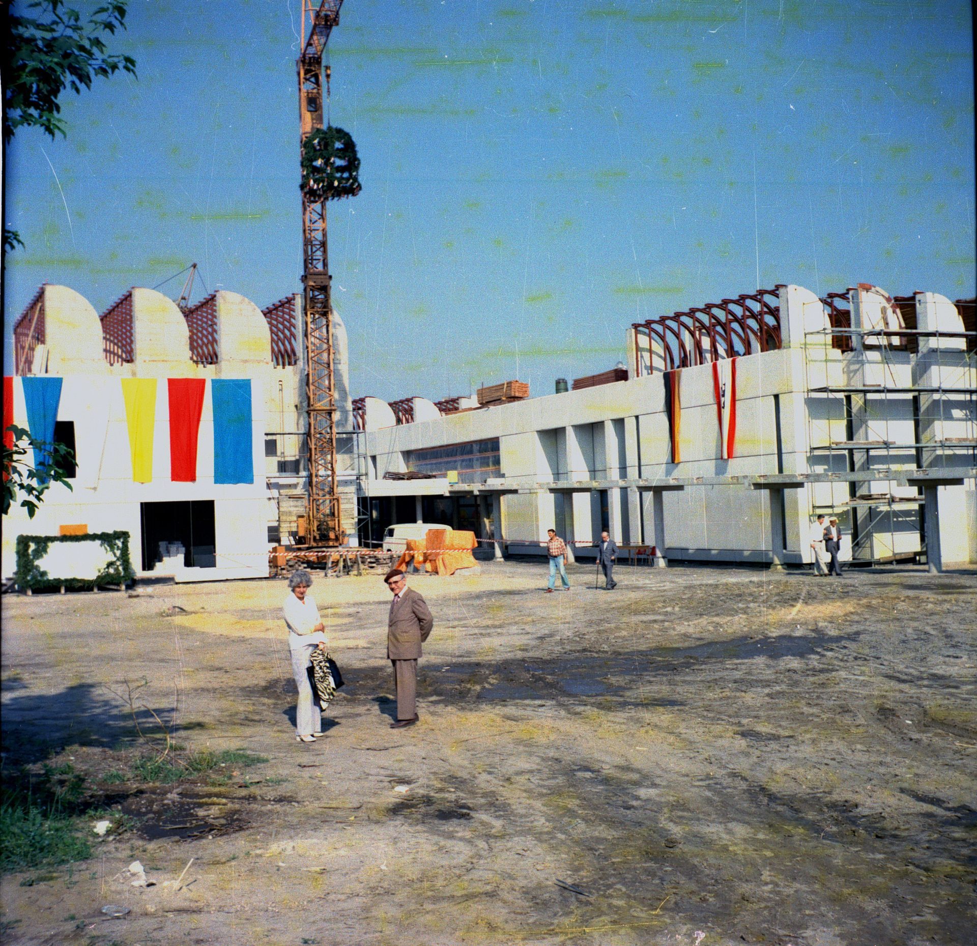 Construction site with a crane, several workers, and colorful facades during the building phase.