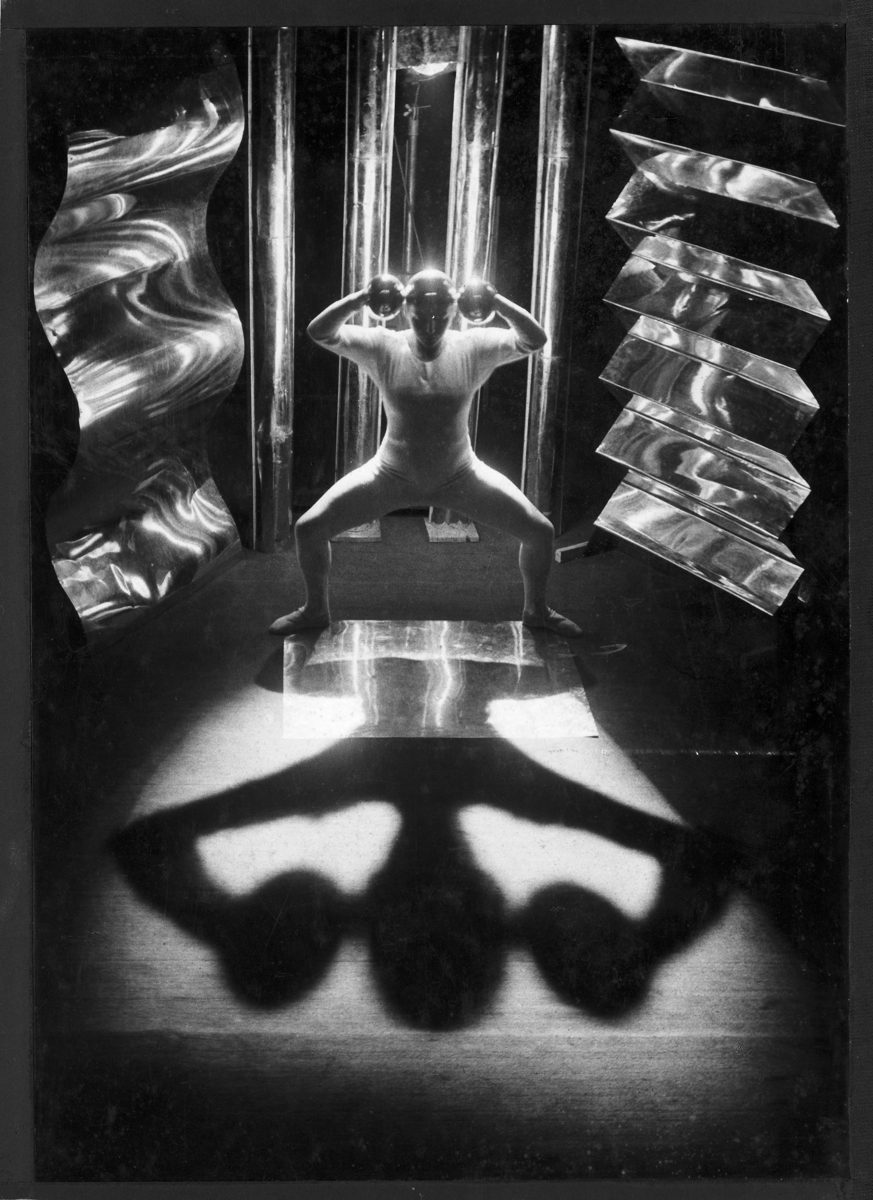 Künstlerisches Schwarz-Weiß-Bild eines posierenden Körpers mit dramatischen Schatten und reflektierenden Elementen.