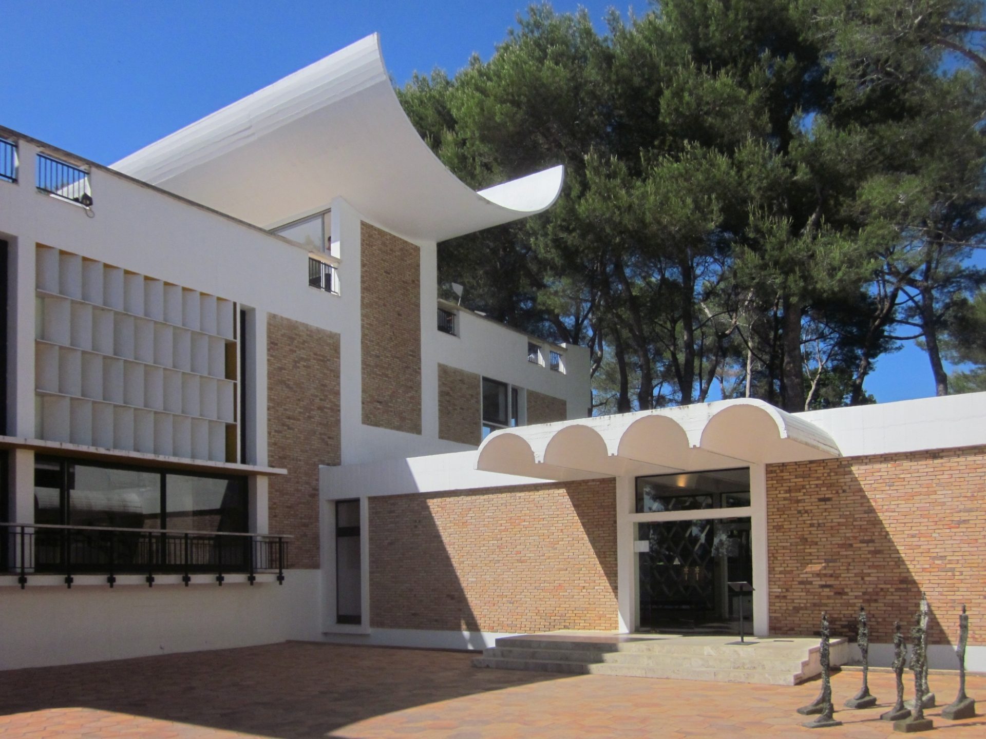 Modern architecture with white and brown materials, slanted roofs, and a green environment.