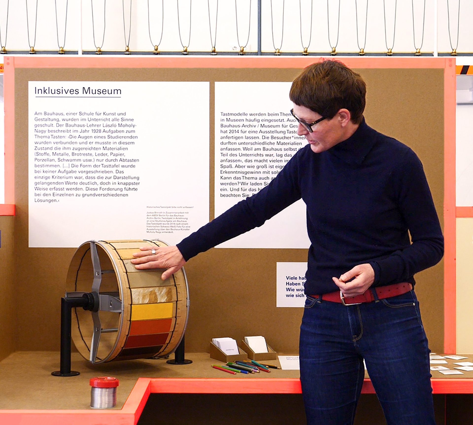 Eine Frau berührt und präsentiert die Tasttrommel, ein taktiles Ausstellungsobjekt.