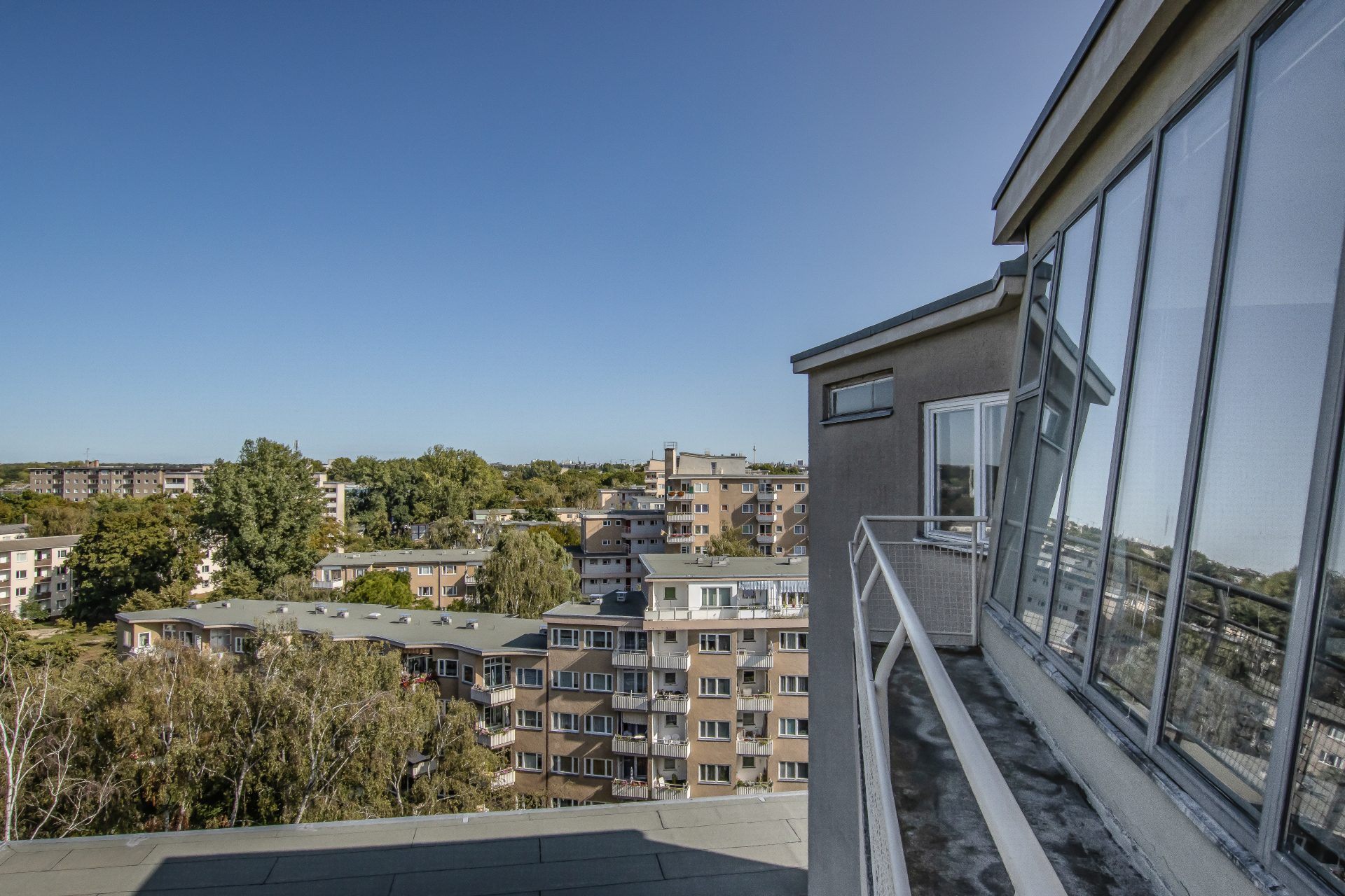 View from a balcony of a neighborhood with residential buildings and a clear blue sky.