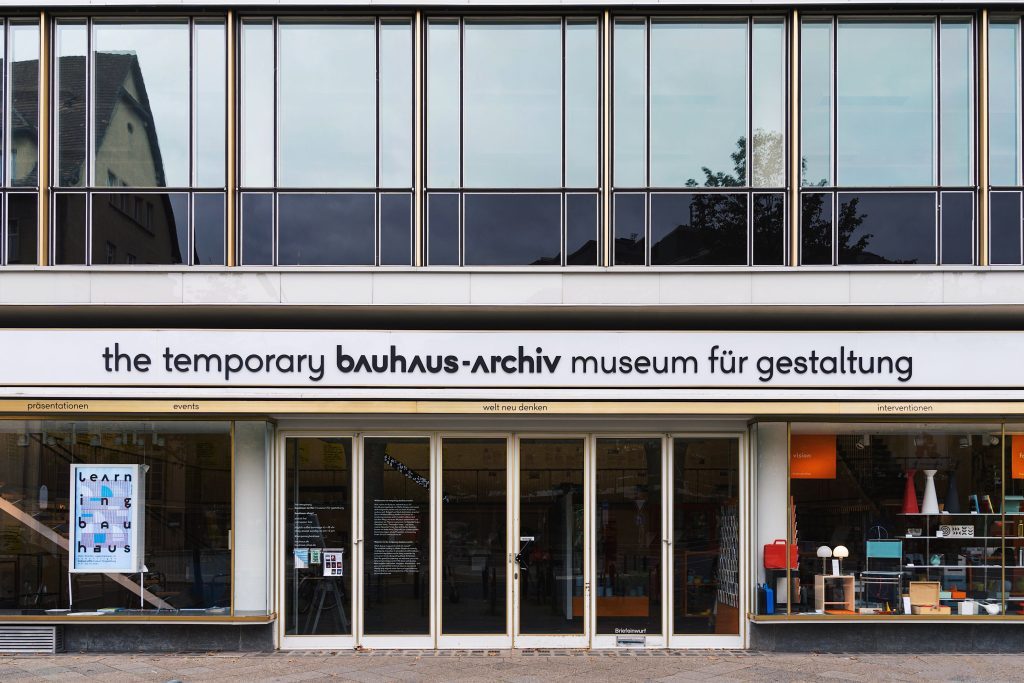 Eingang des temporären Bauhaus-Archivs, einem Museum für Gestaltung, mit modernen Fenstern und dekorativen Elementen.