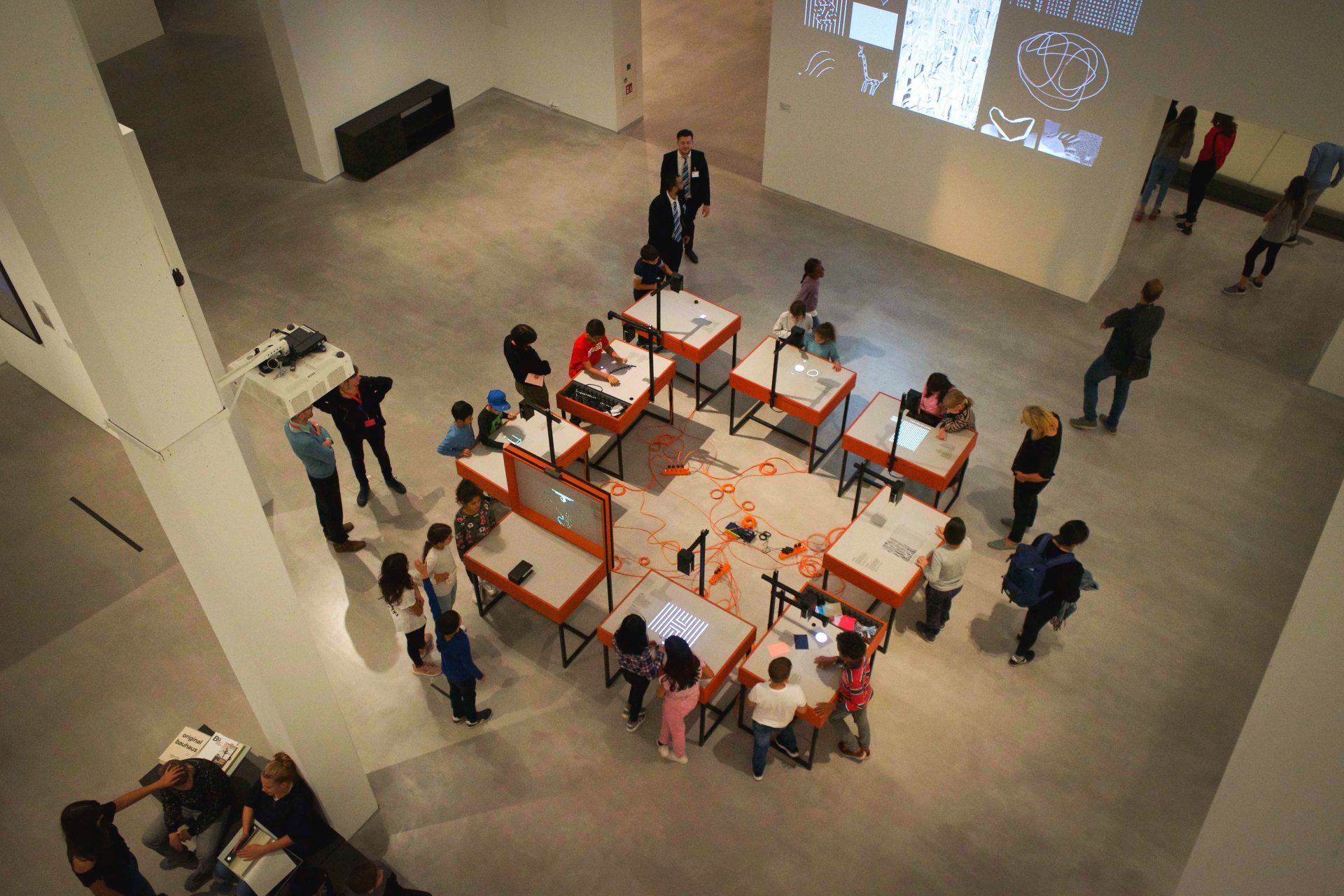 Eine Gruppe von Kindern arbeitet an Tischen in einem modernen Ausstellungsraum.