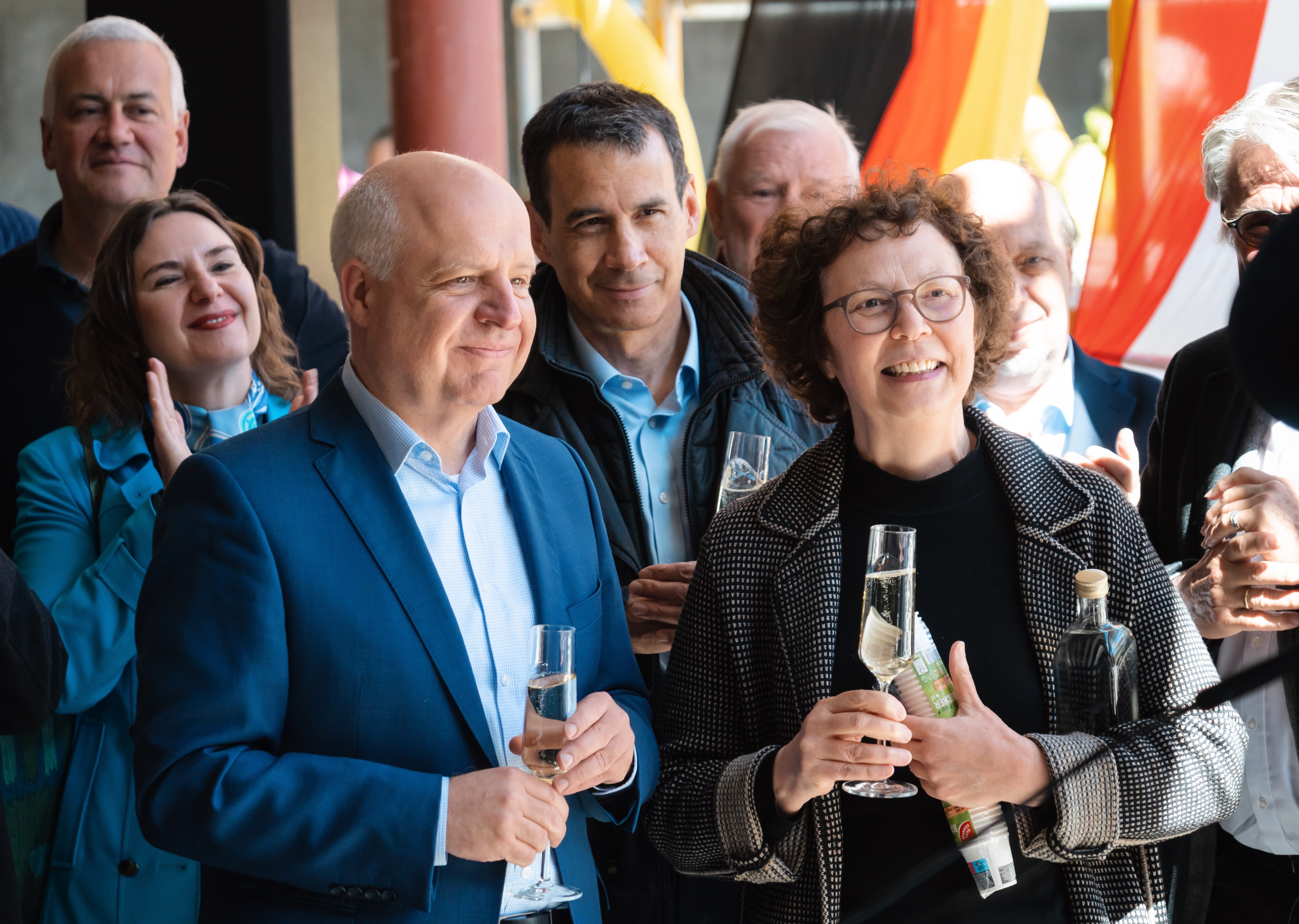 Gruppenszene mit Menschen, die anstoßen und lächeln, in einem festlichen Ambiente.