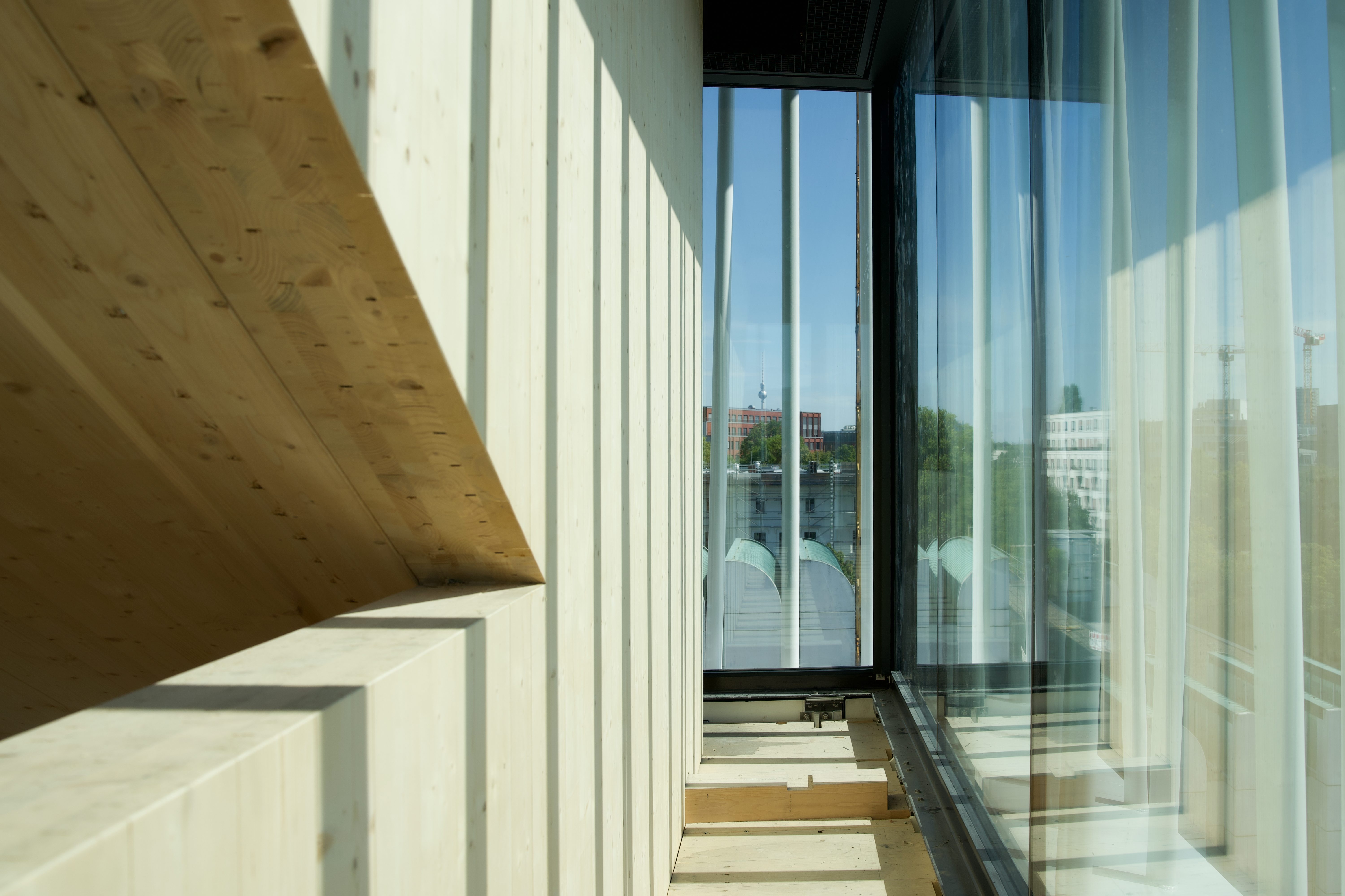 Moderne Architektur mit Holz- und Glaselementen, große Fenster bieten Blick auf den Außenbereich.