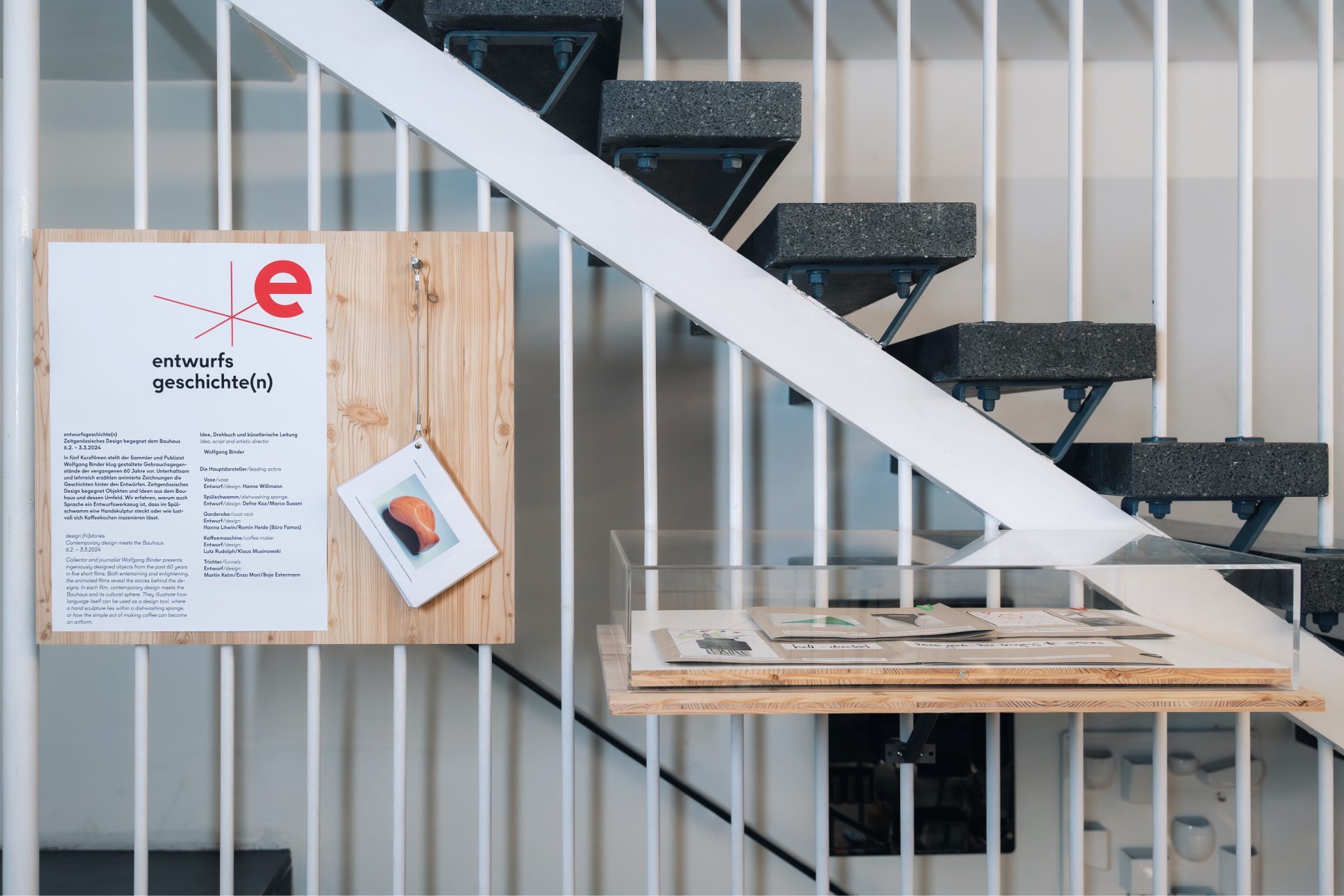 Ausstellungstafel an einer Treppe mit Informationen und Objekten in einem modernen Umfeld.