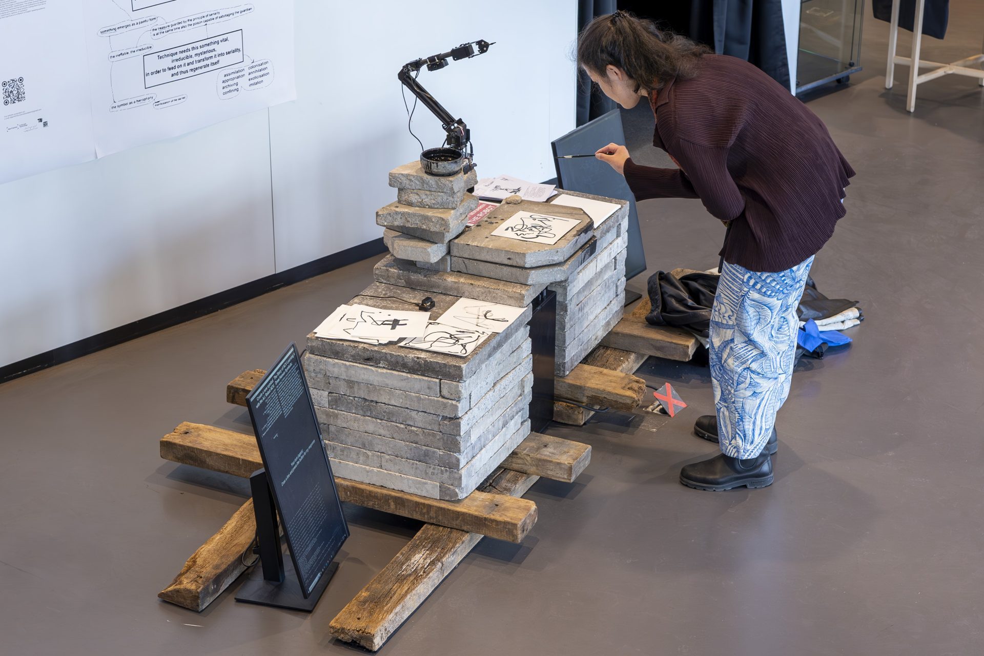 Person untersucht ein Ausstellungsobjekt auf einer Holzplattform mit Lampe in einem modernen Raum.