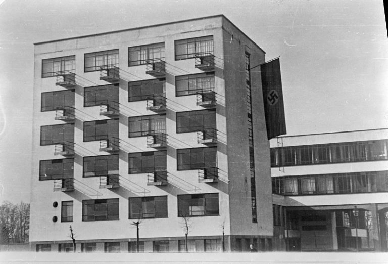 Historisches Gebäude mit rechteckigen Fenstern, Balkonen und einer Flagge; in Schwarz-Weiß dargestellt.