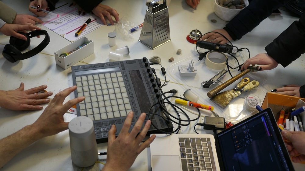 Tisch mit verschiedenen Werkzeugen, Laptops und kreativen Materialien für eine interaktive Sitzung oder einen Workshop.
