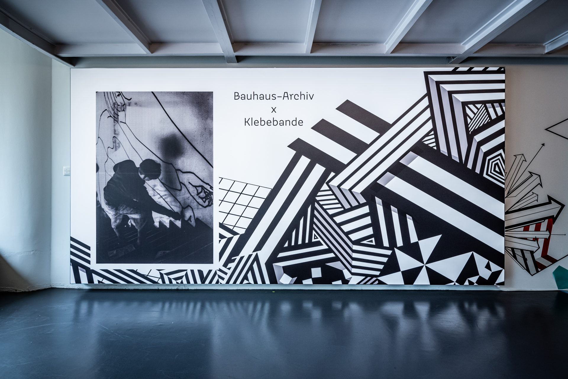 Wandgestaltung mit schwarz-weißen geometrischen Mustern und dem Schriftzug "Bauhaus-Archiv x Klebebande".