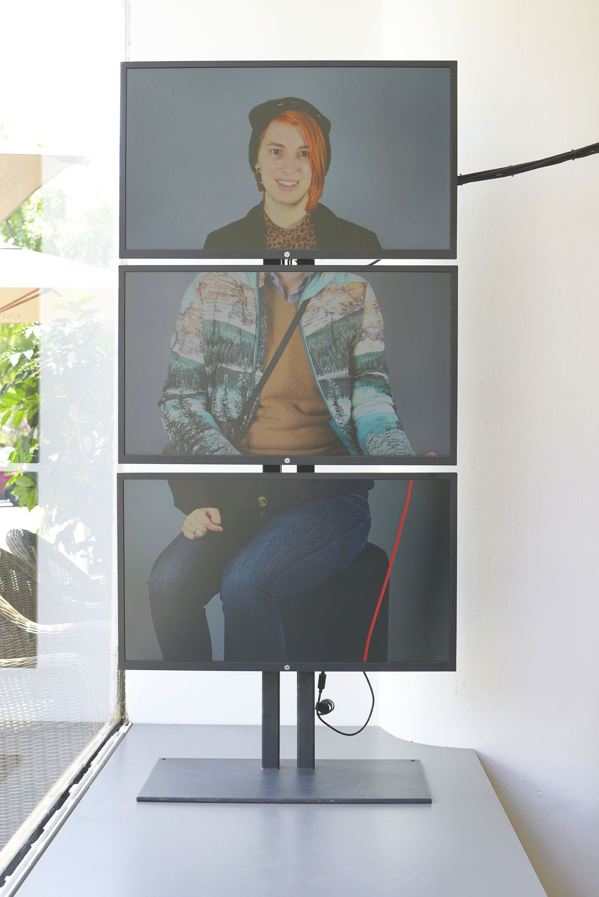 Drei übereinander stehende Monitore zeigen verschiedene Portraits einer Person in modernem und lässigem Kleidungsstil.