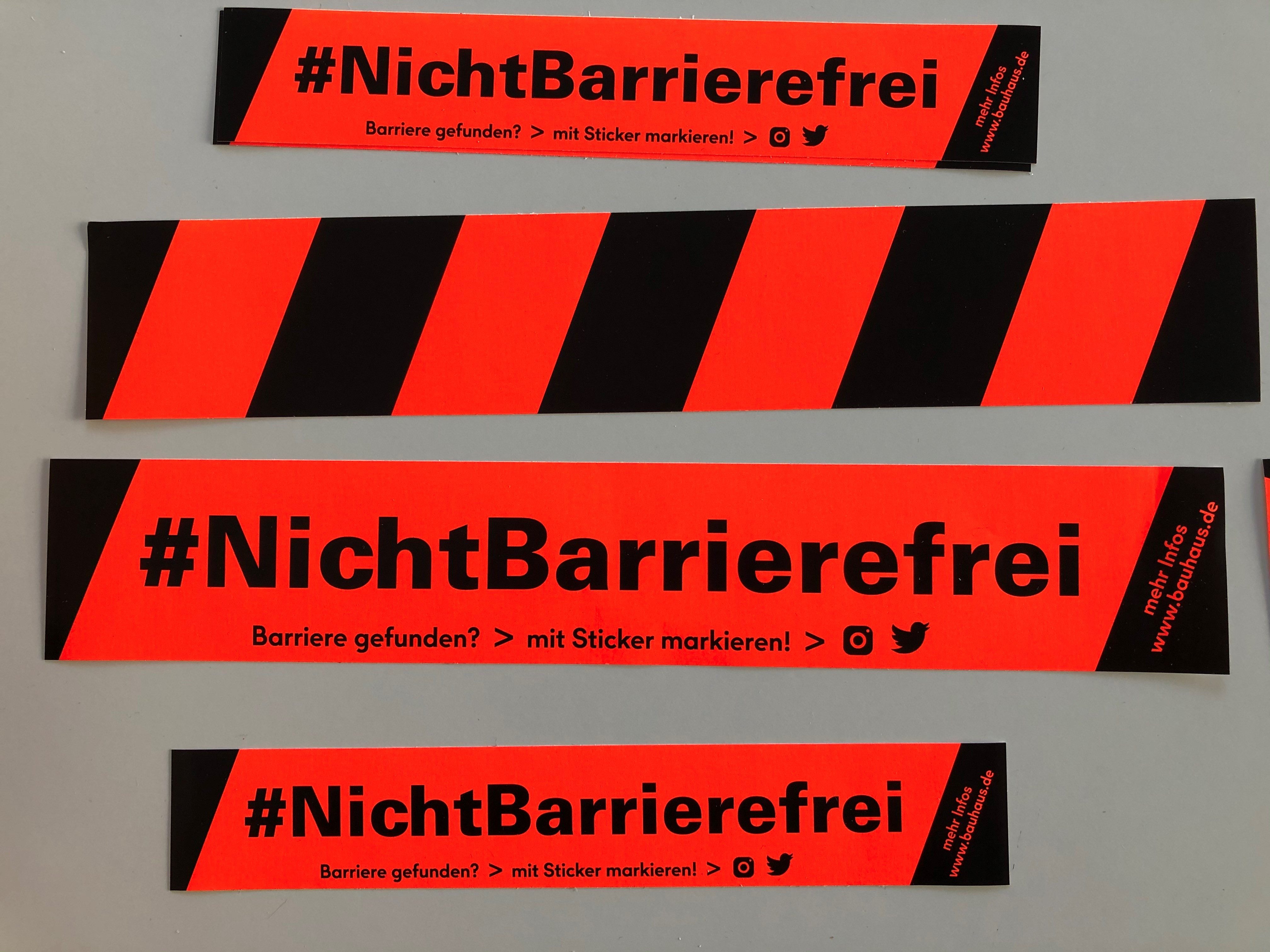 Rote Aufkleber mit dem Text „#NichtBarrierefrei“ und Informationen zur Meldung von Barrieren.