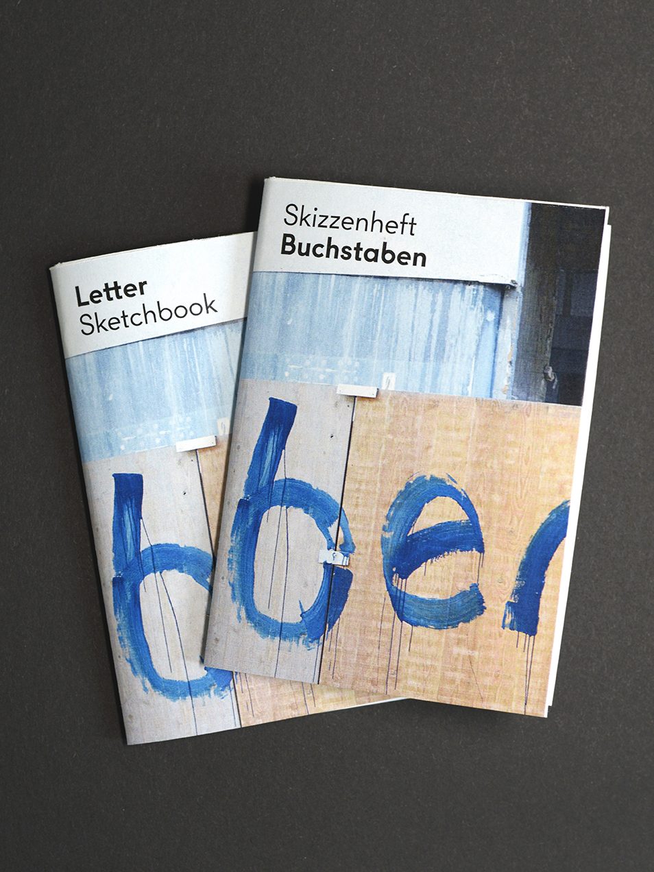 Zwei Skizzenhefte mit den Titeln „Letter“ und „Buchstaben“ auf dunklem Hintergrund.