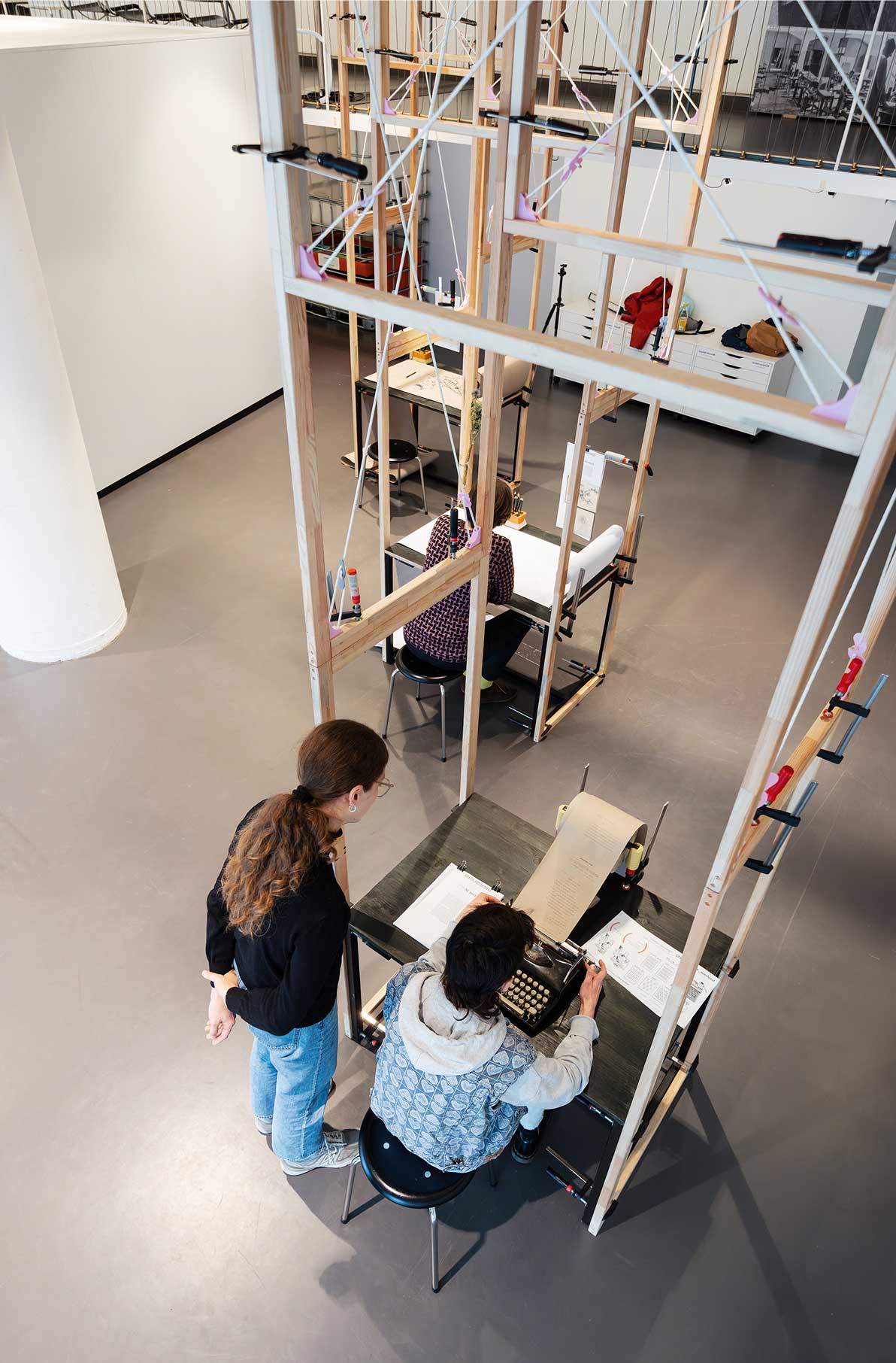 Zwei Personen arbeiten in einem modernen, offenen Raum mit Tischen und kreativen Holzstrukturen.