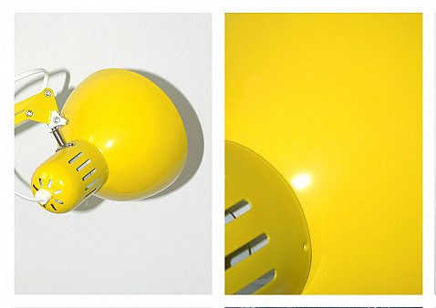 Gelbe Metalltischlampe mit runder Form, seitlicher Halterung und Lüftungsschlitzen.
