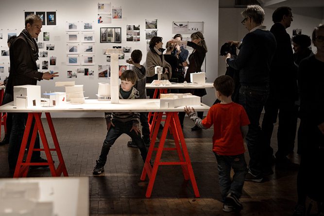 Kinder und Erwachsene in einem Ausstellungsraum, wo Modelle und Fotografien präsentiert werden.