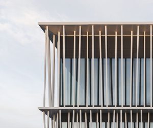 Moderne Architektur mit Glasfassade und vertikalen Strukturen unter einem klaren Himmel.