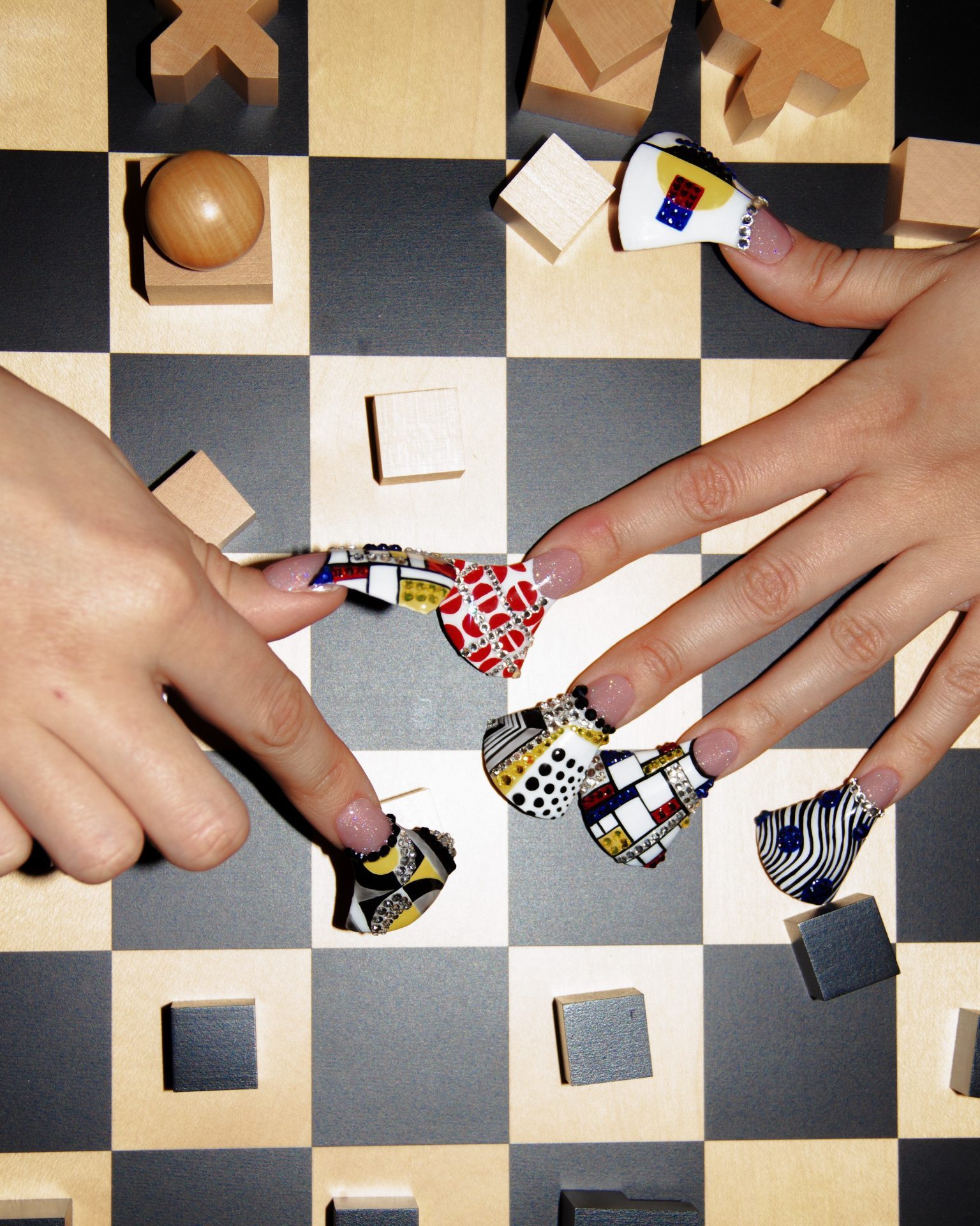 Bunte, kunstvoll gestaltete Nägel bewegen Schachfiguren auf einem Schachbrett.