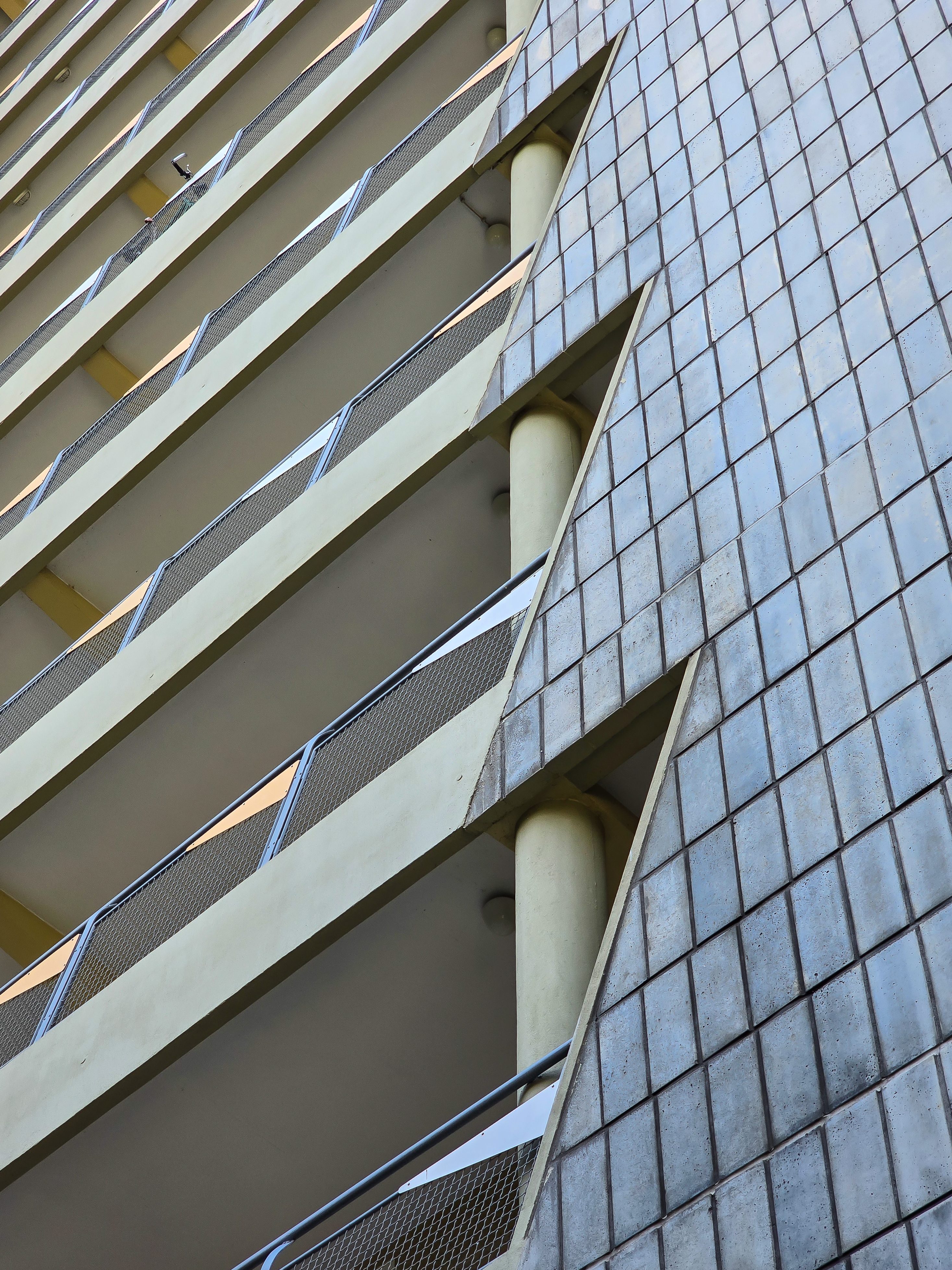 Modernes Gebäude mit geschwungenen Balkonen und geometrischen Fassadenelementen, vertikal fotografiert.