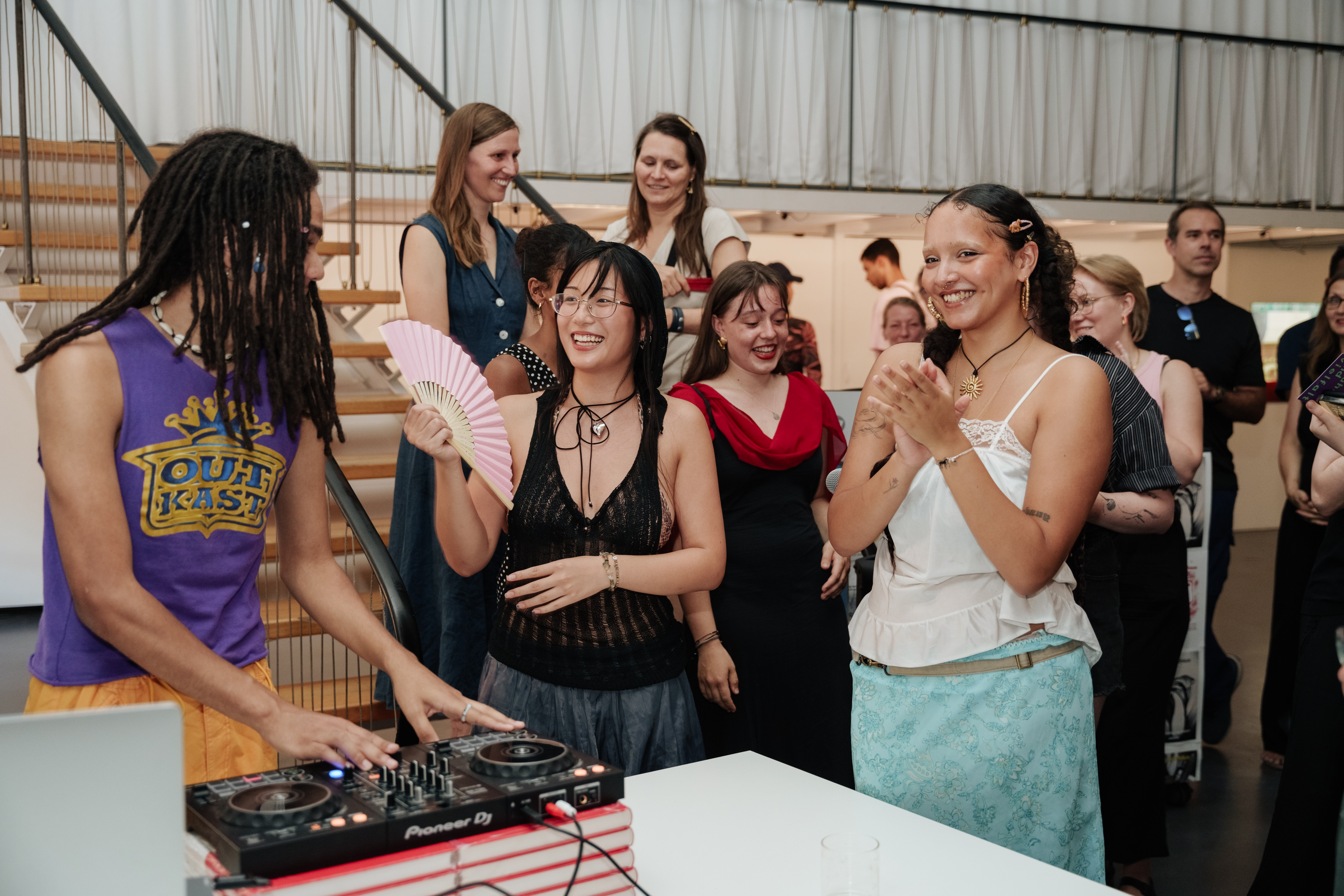 Eine lebhafte Feier mit fröhlichen Menschen, Musik und Tanz, während jemand an den DJ-Decks auflegt.