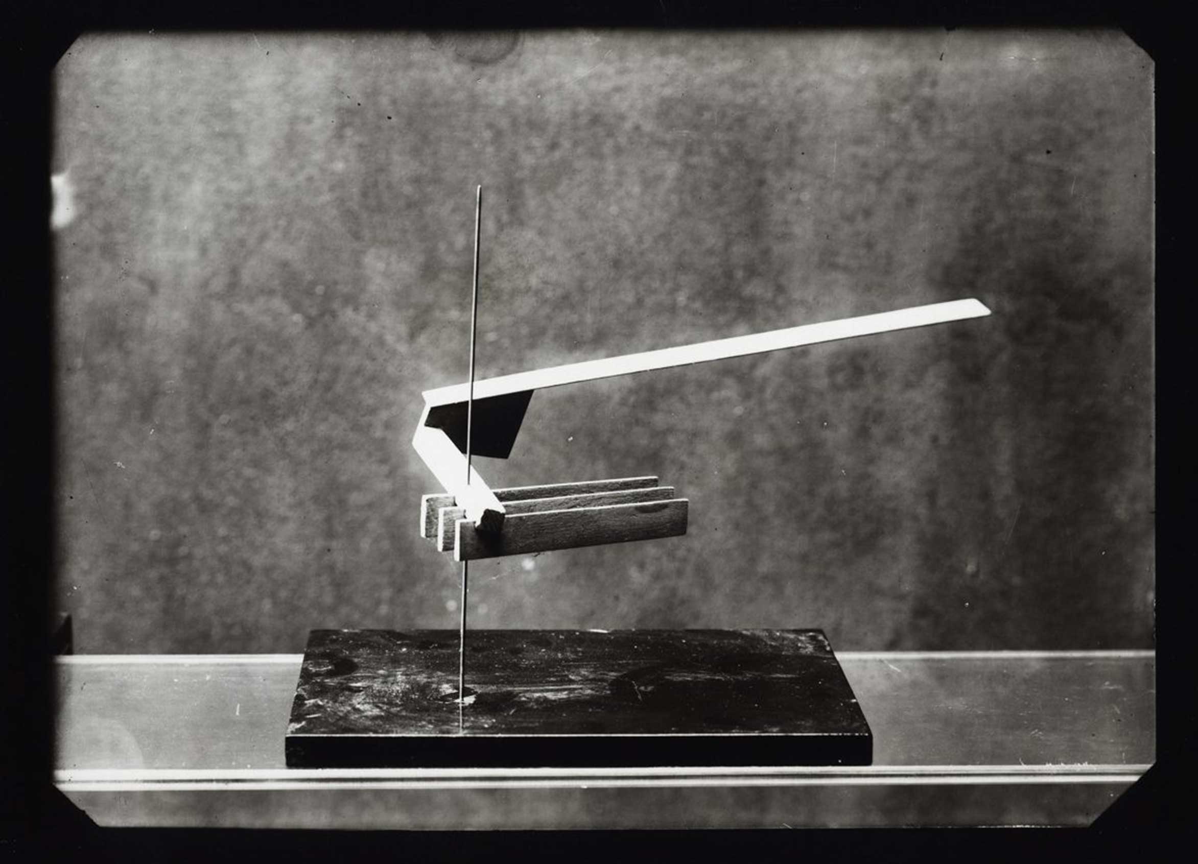 Abstract sculpture made of wood and metal, balancing on a dark base. Minimalist design in black and white.