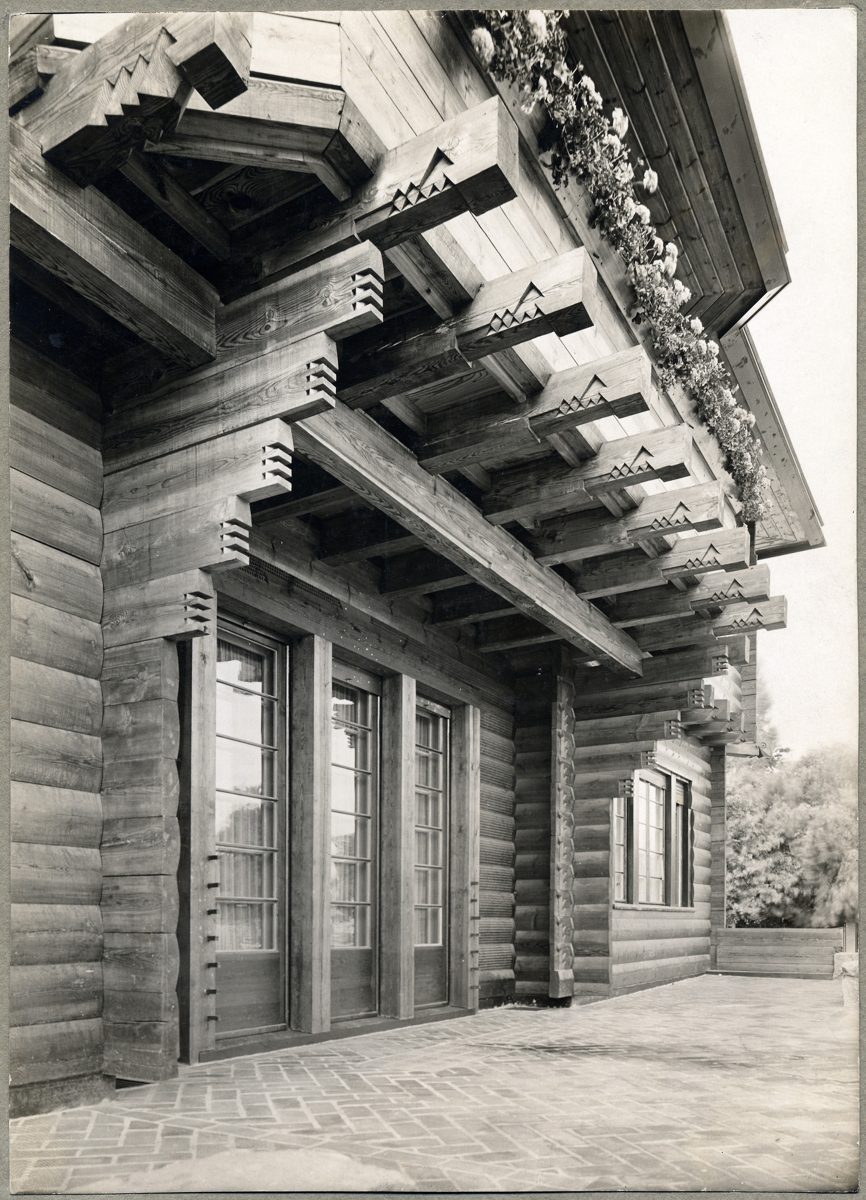 Close-up of wooden architecture with carved beams and large windows. Historical style, black-and-white photograph.