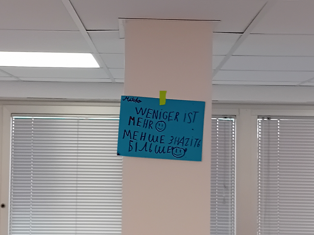 Bunter Zettel an der Wand mit "Weniger ist mehr" in verschiedenen Sprachen.