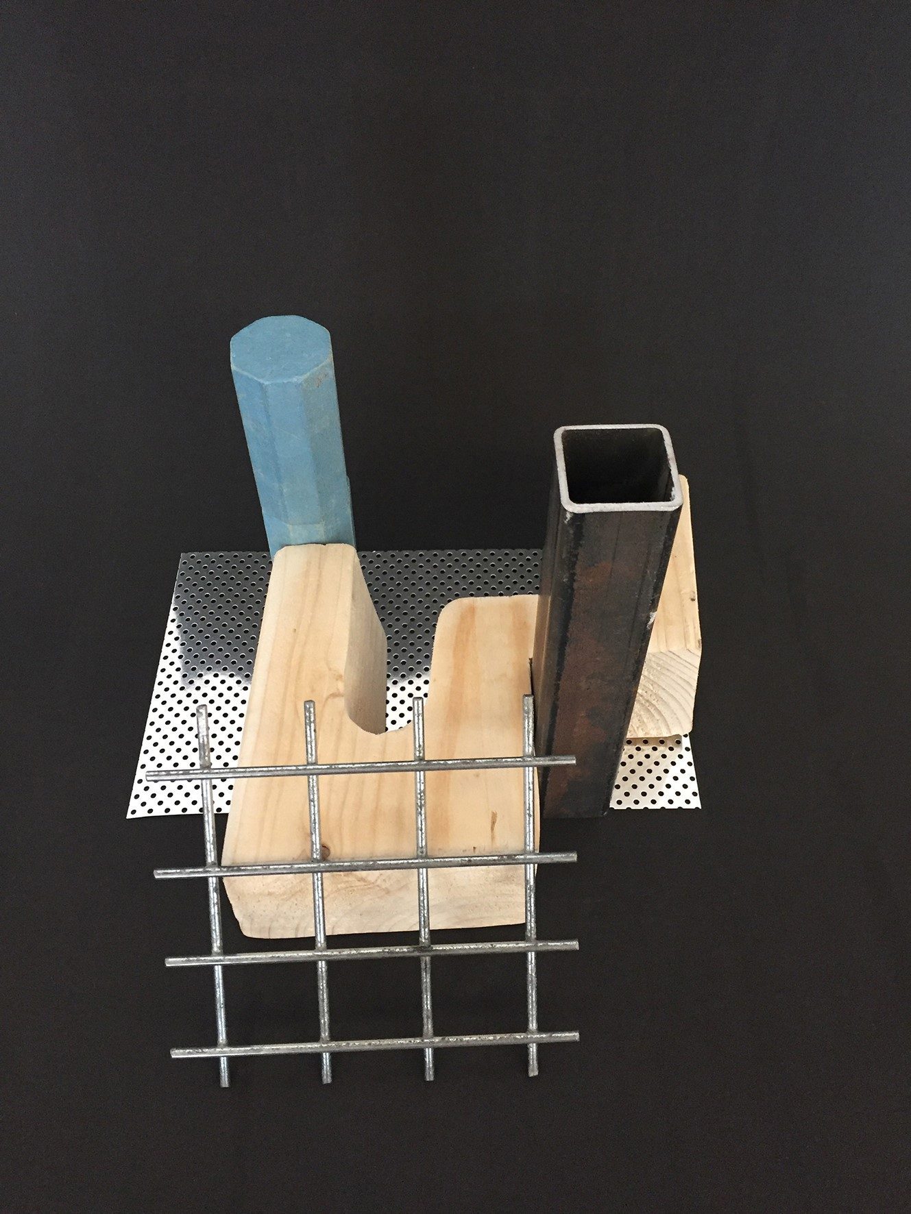 Kreative Anordnung aus Holz, Metall und Drahtgeflecht auf schwarzem Hintergrund mit geometrischen Formen und Texturen.