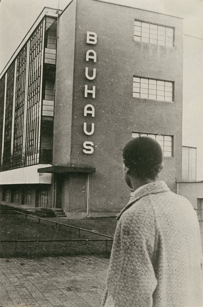Person vor dem Bauhaus-Gebäude; historische Schwarz-Weiß-Aufnahme mit prägnanter Architektur.