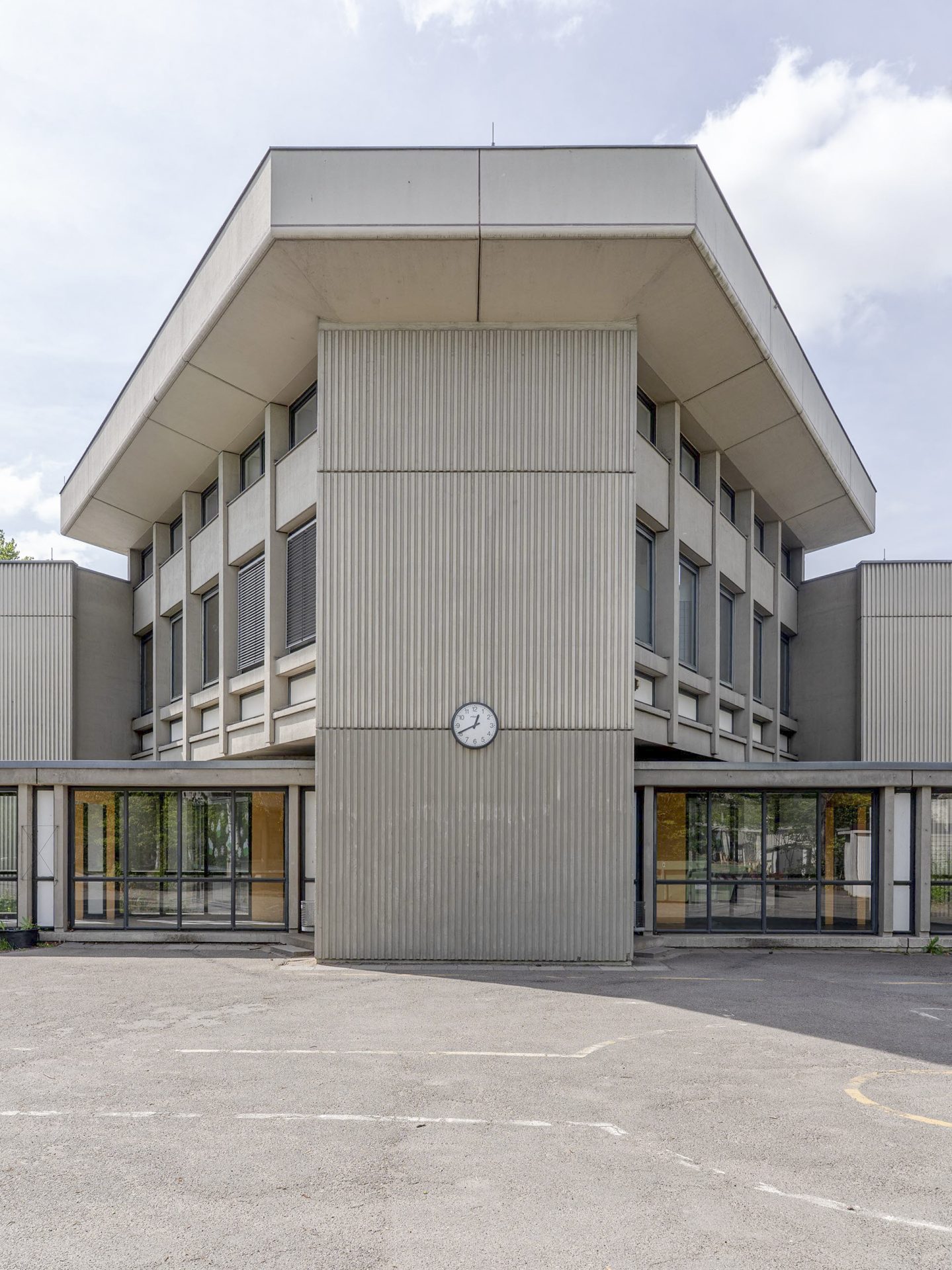 Zu sehen ist eine Frontalansicht der Walter Gropius Schule mit einer Uhr an der Fassade.