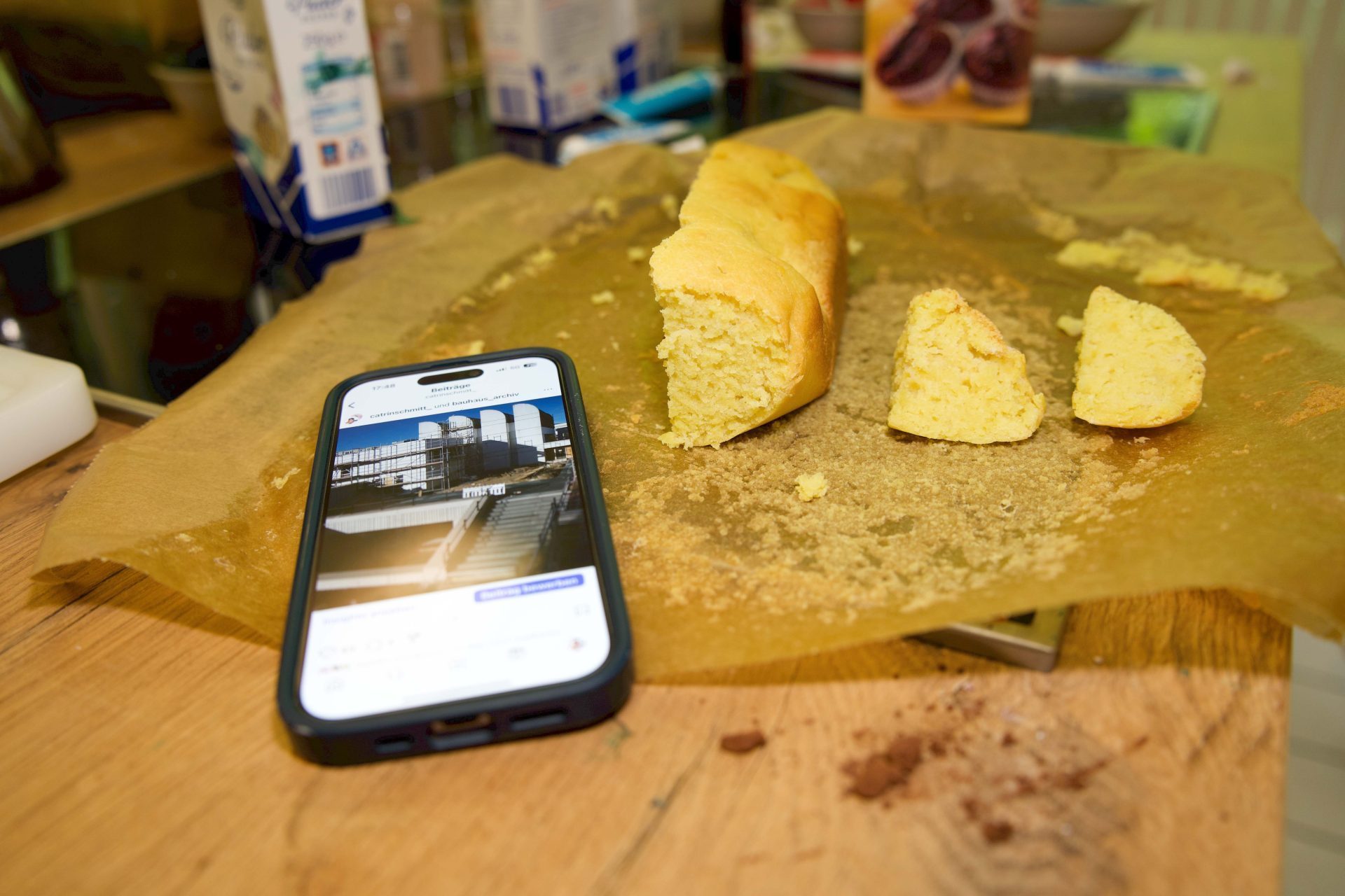 Schneebrotstücke liegen auf Backpapier neben einem Smartphone mit einem Foto von Architektur.