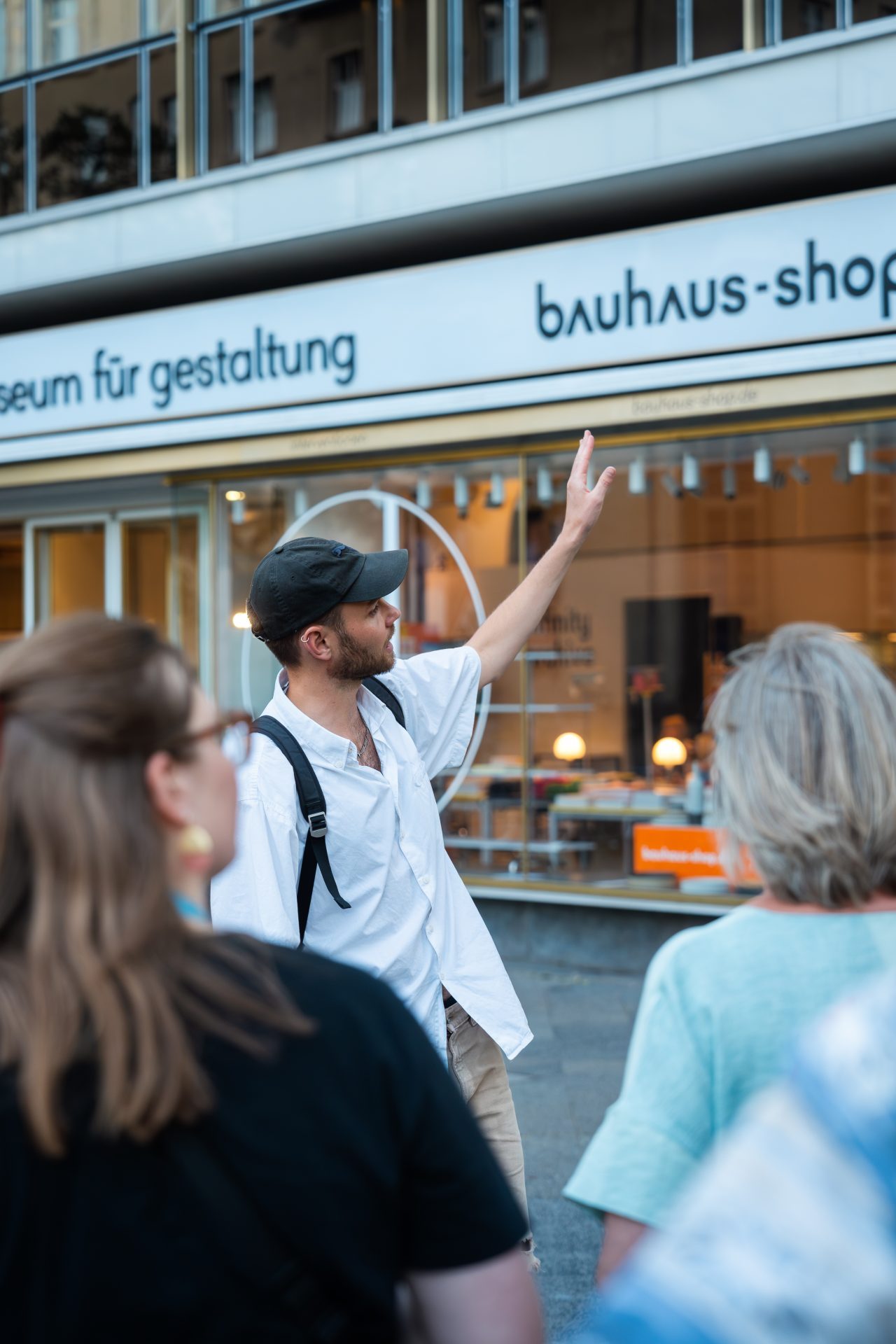 Ein Guide erklärt vor dem Bauhaus-Shop, während eine Gruppe von Menschen gebannt zuhört.