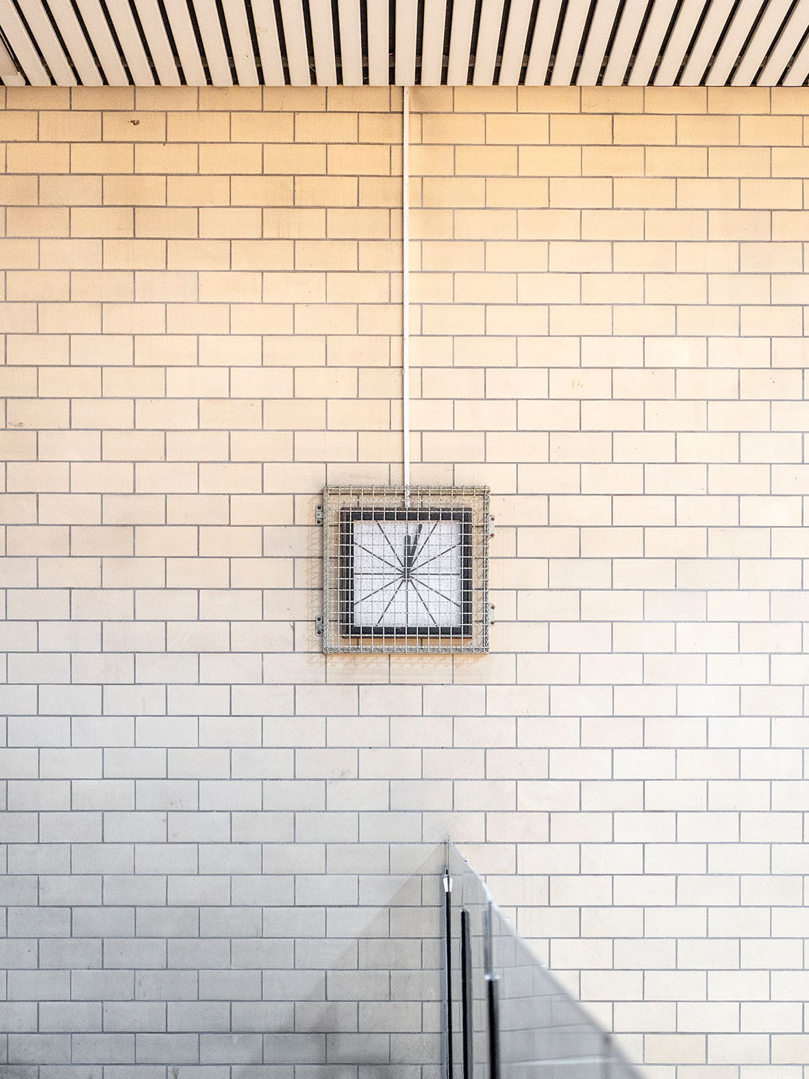 Minimalist image of a wall with a rectangular frame and graphic design. Bright tiles in the background.