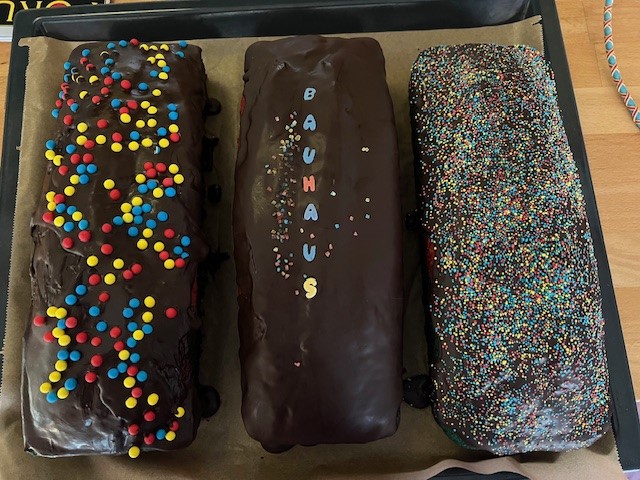 Three chocolate cakes with colorful sprinkles and the text "BAUHAUS" on the middle cake.