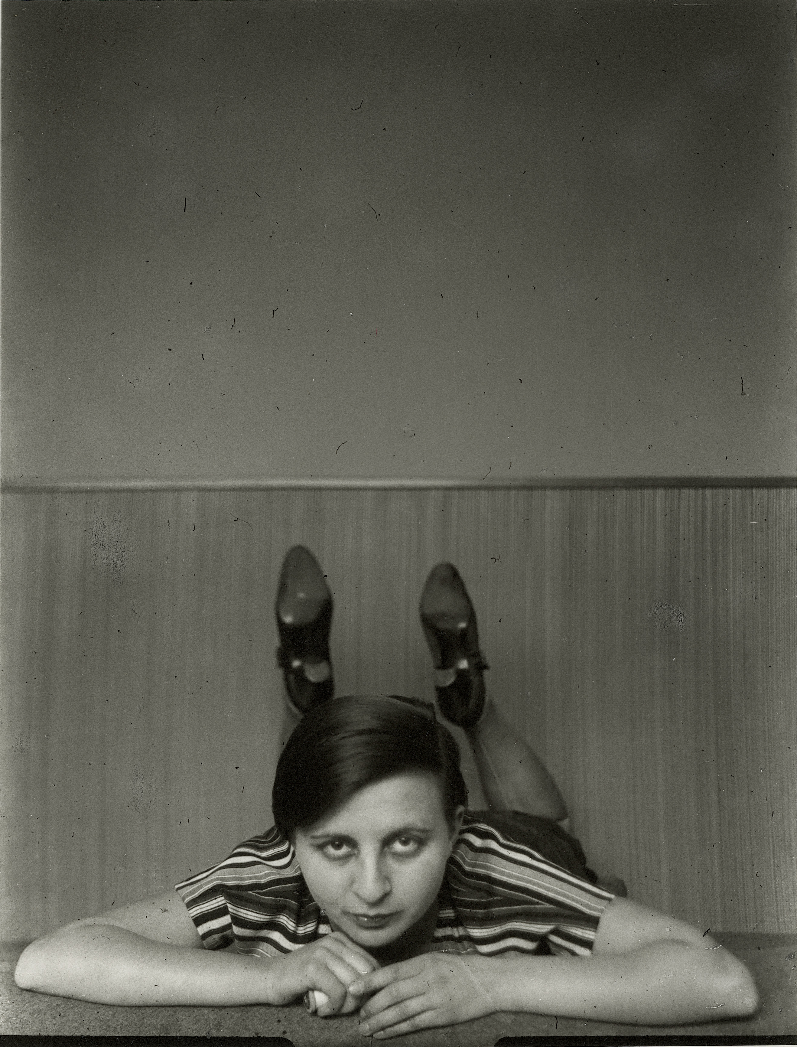 Frau in gestreiftem Shirt liegt auf dem Bauch und schaut direkt in die Kamera, monochrome Fotografie.