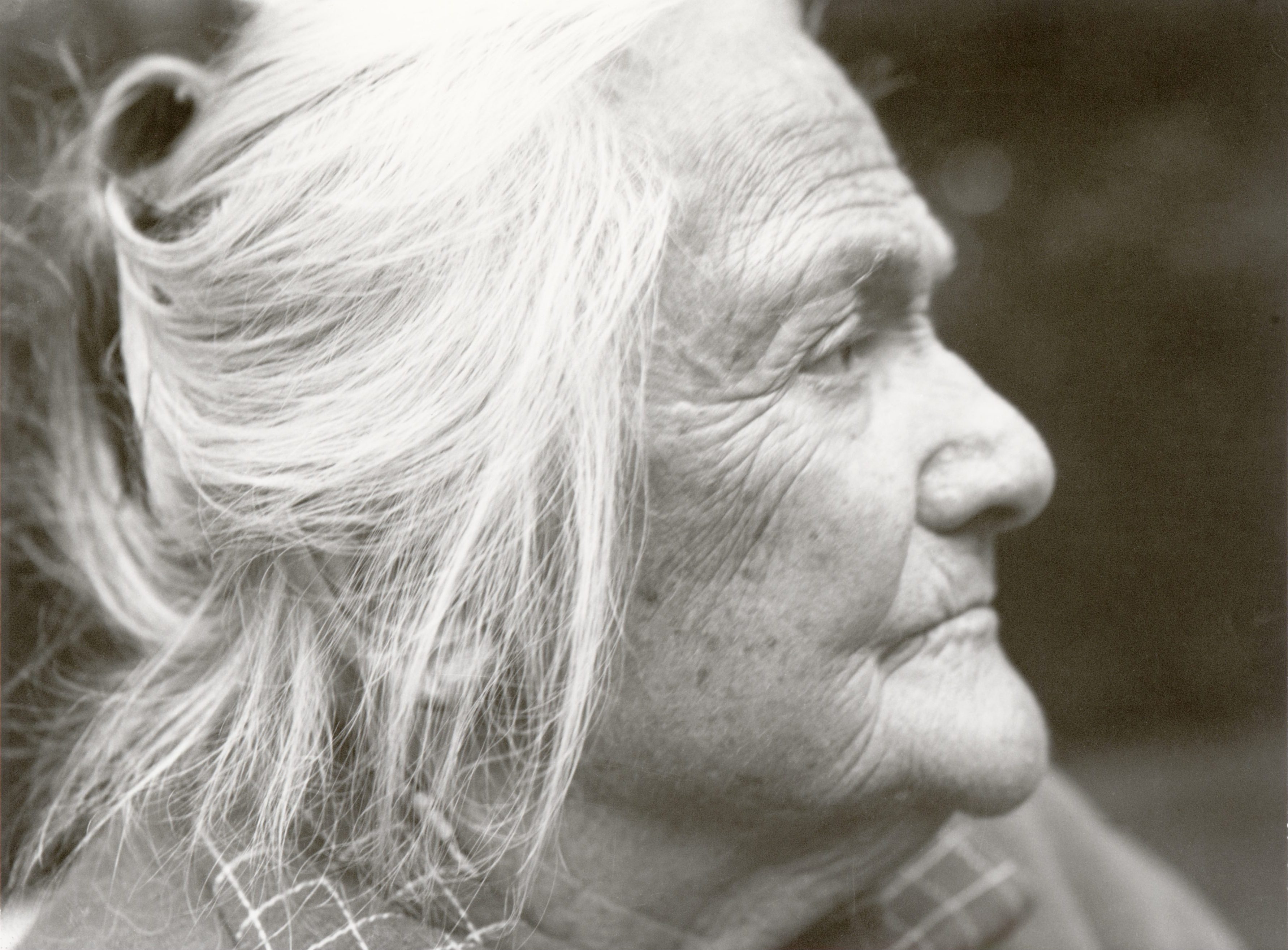 Portrait of an older woman in profile with a holistic expression and gray hair. Presented in black and white.