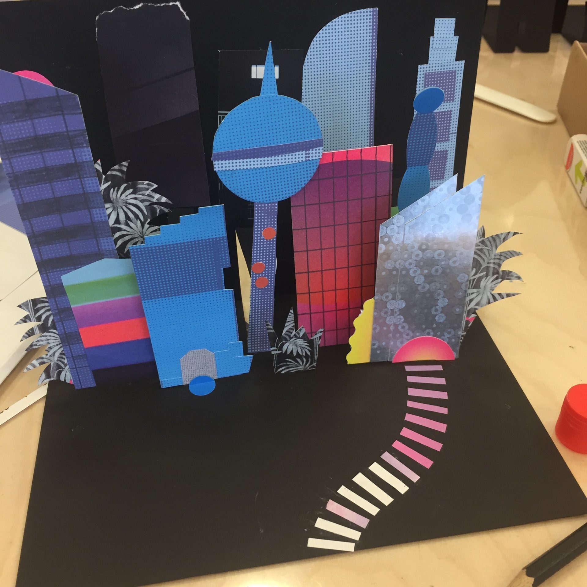 Das Foto zeigt eine aufgeklappte schwarze Pop-Up Karte mit einer Großstadt-Kulisse aus farbigen Gebäuden.
