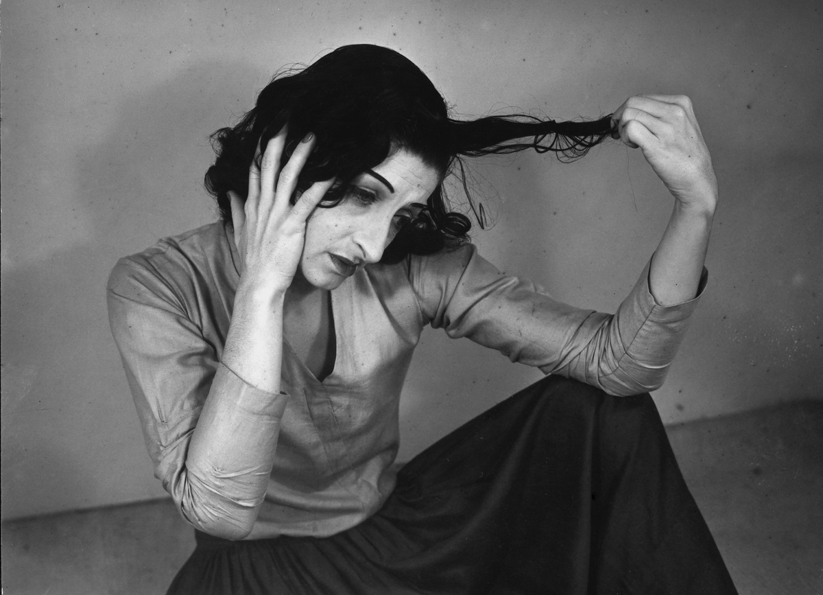 Schwarz-weiß Foto einer nachdenklichen Frau, die mit melancholischem Ausdruck sitzt und sich die Haare hält.