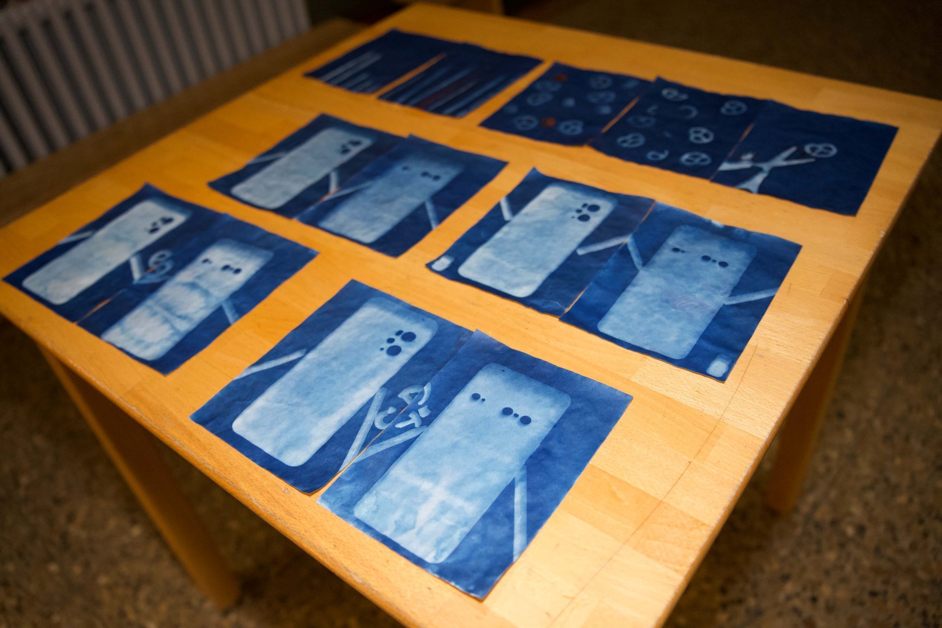 On a wooden table lie several blue sheets with transparent motifs and patterns.