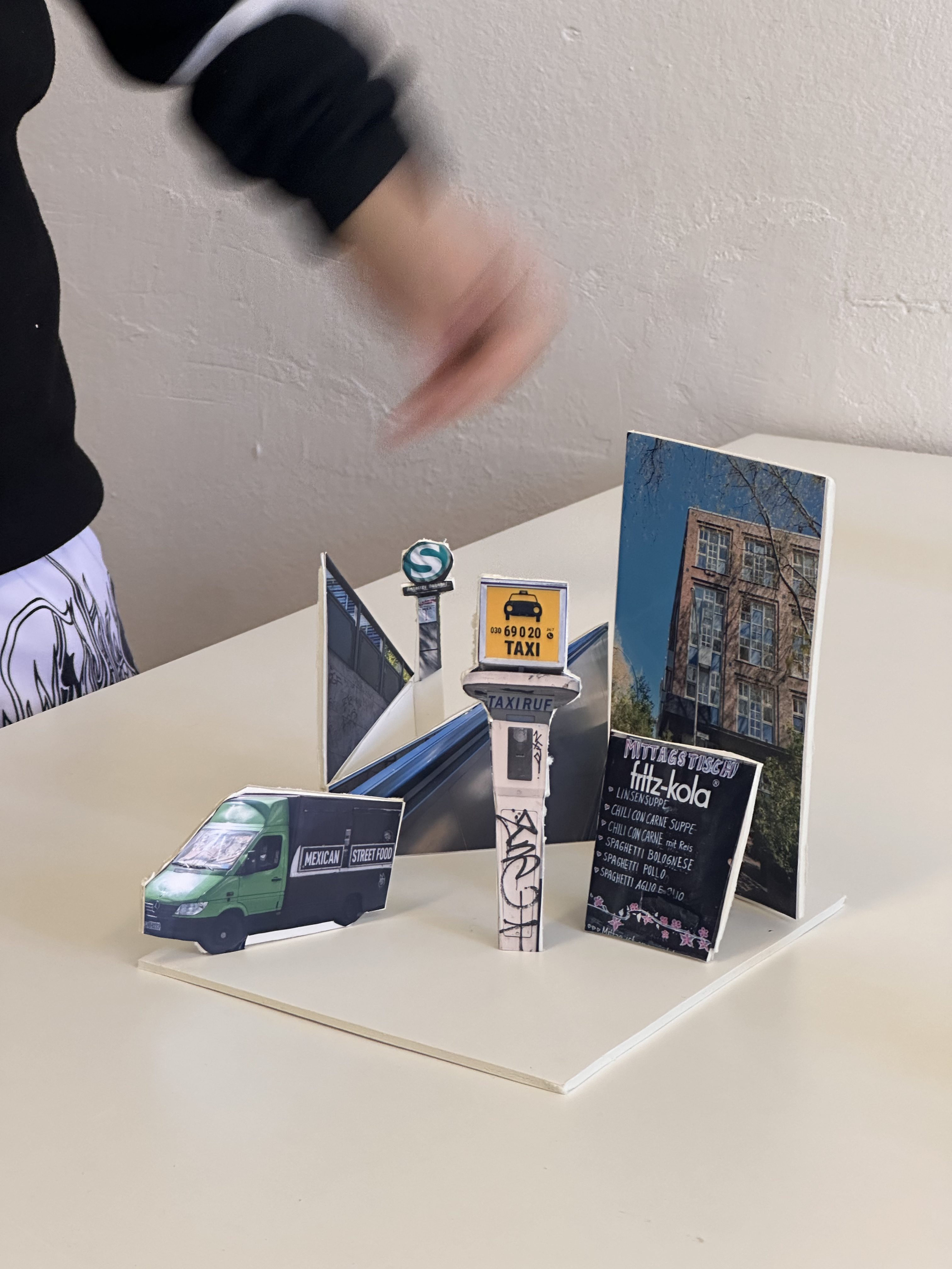 Pop-up-Szene mit verschiedenen Miniaturobjekten: Taxi, Food Truck und Fotos auf einem Tisch.