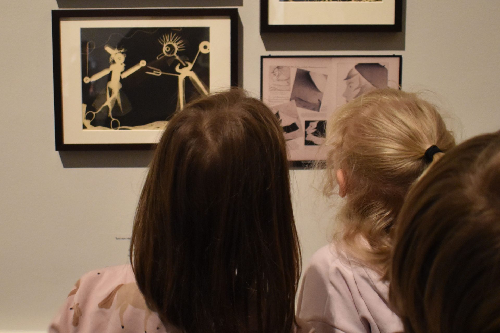 Zwei Kinder betrachten Kunstwerke an der Wand in einem Ausstellungsraum.