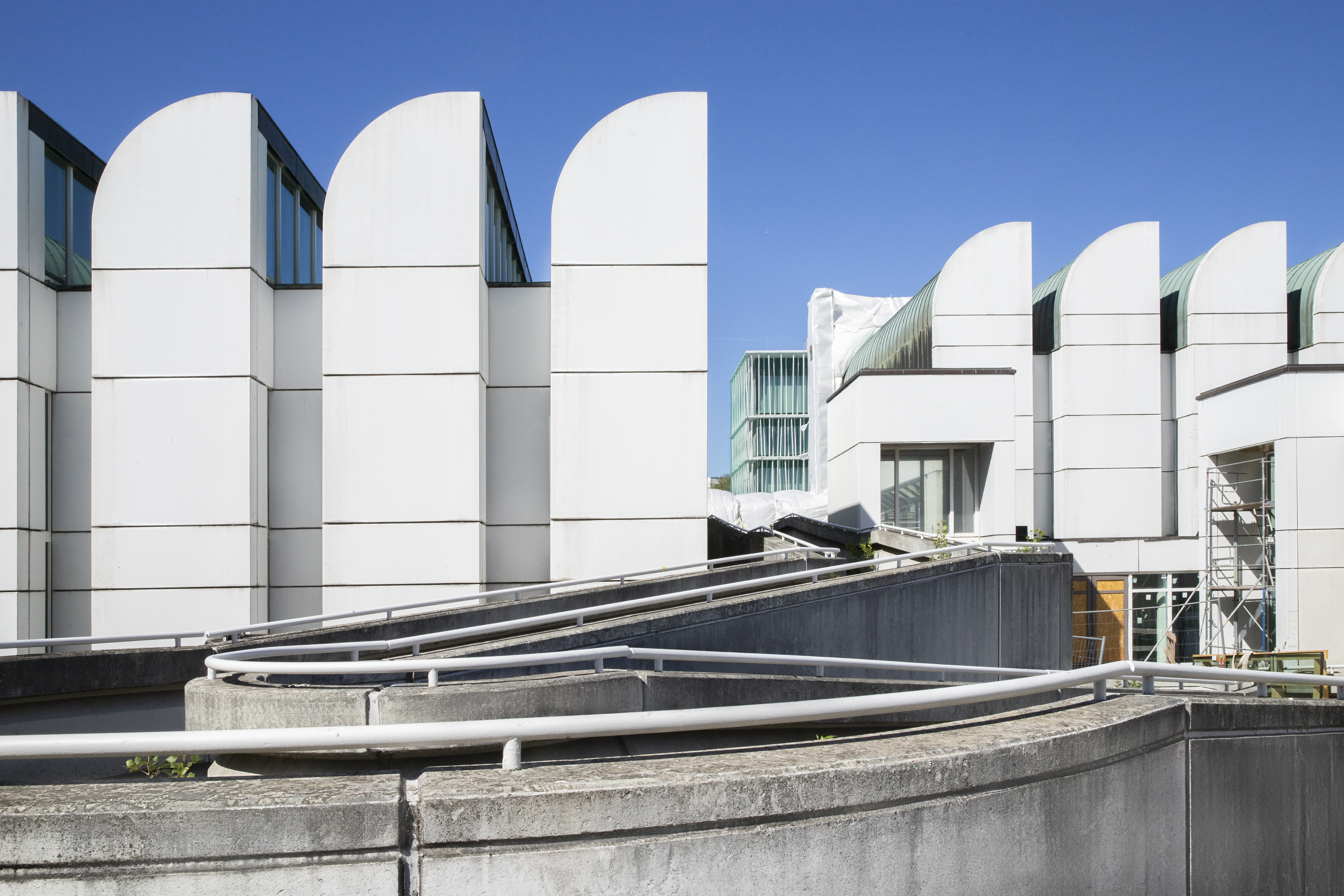 Moderne Architektur mit geschwungenen Elementen und klaren Linien unter blauem Himmel.