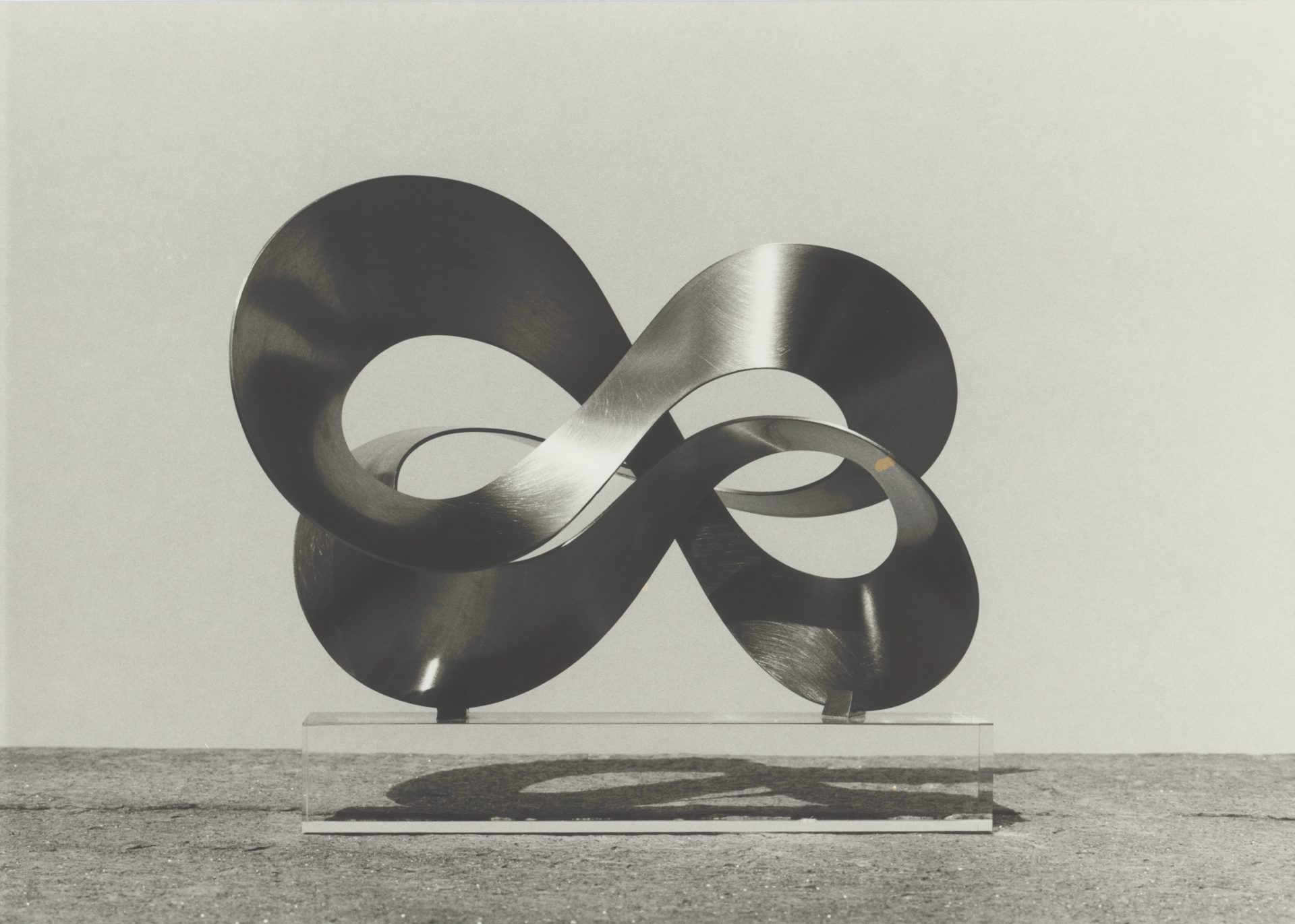 Modern stainless steel sculpture representing an infinity symbol, featuring clear lines and shadows.