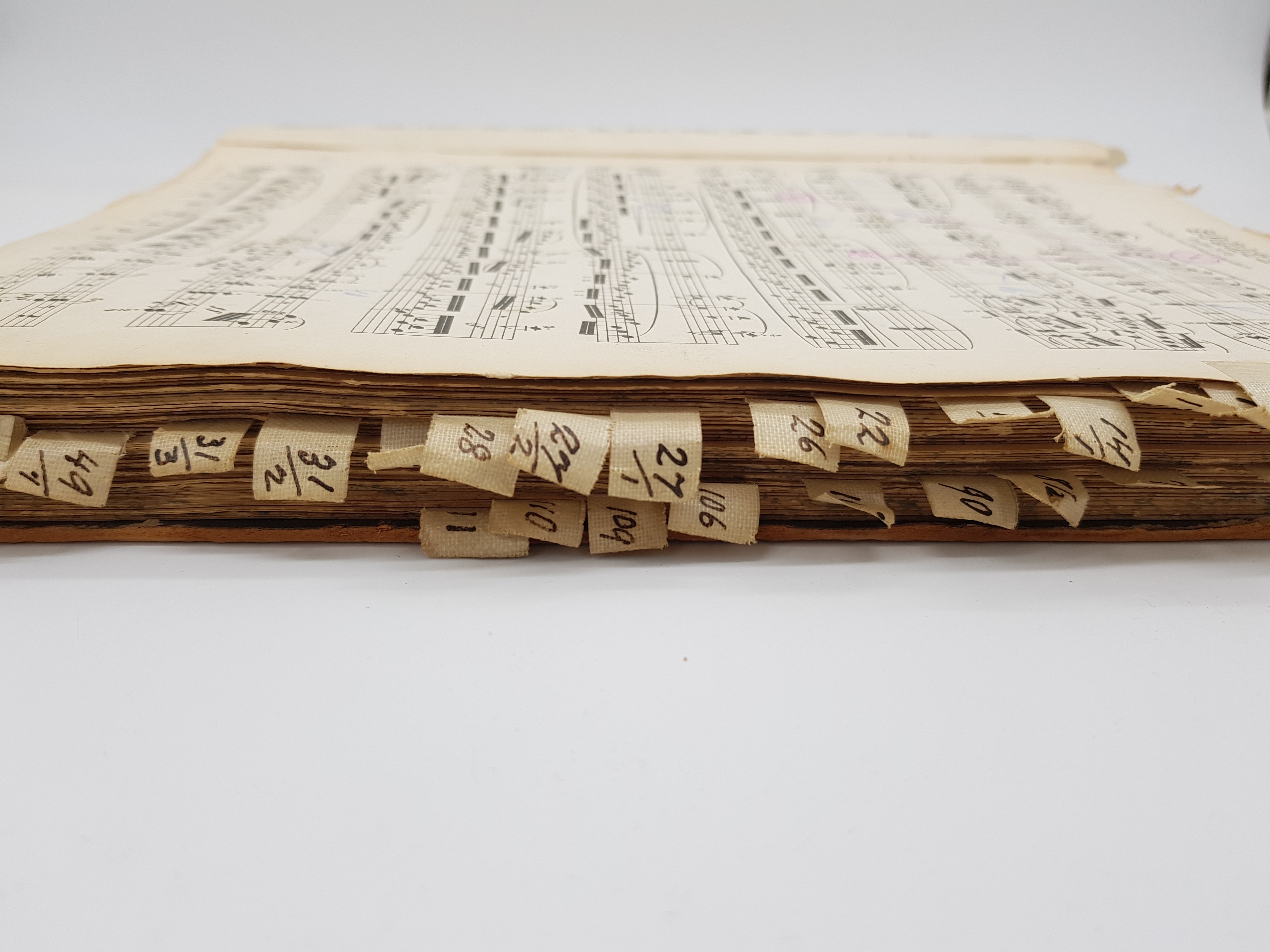 Ein aufgeschlagenes Buch mit Musiknoten und indexierten Seitenmarkierungen aus Papier.