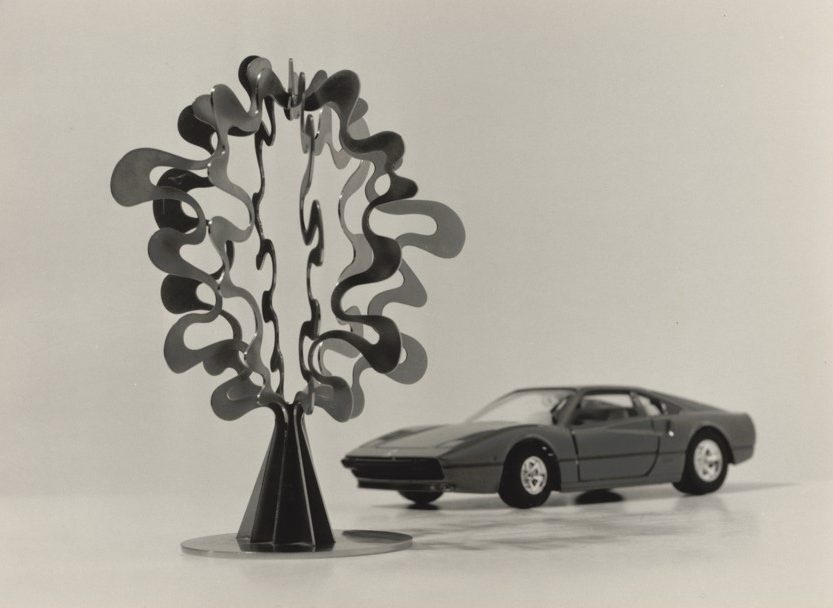 Modern sculpture and a model car in a black-and-white setting. Art meets automotive design.