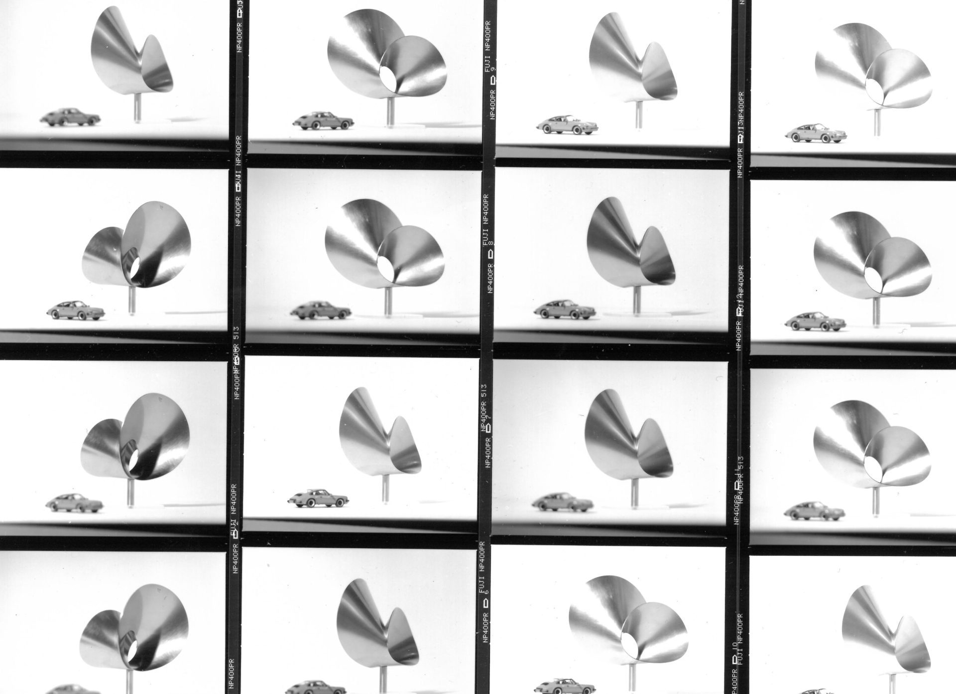 Black and white image with metallic sculptures and a model car arranged in several sections.